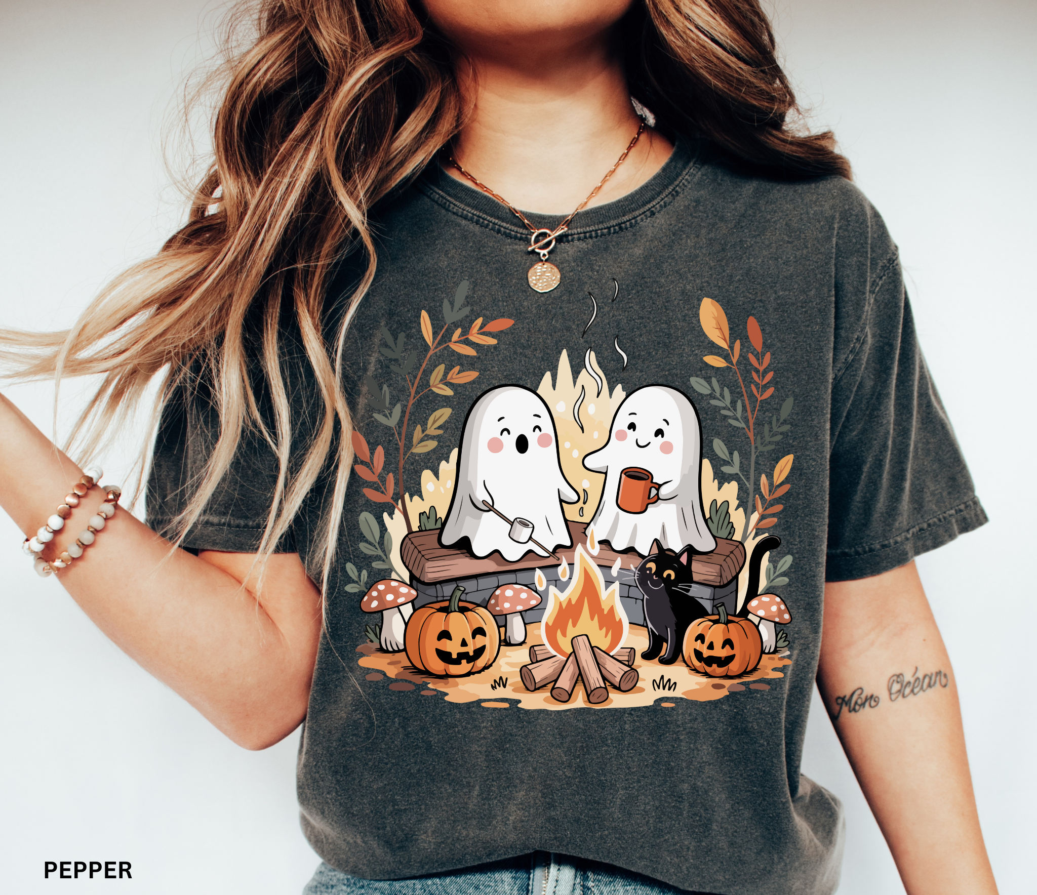 Halloween shirt design featuring two cute ghosts by a campfire, one roasting marshmallows, one holding cocoa, with pumpkins, mushrooms, fall leaves, and a black cat.