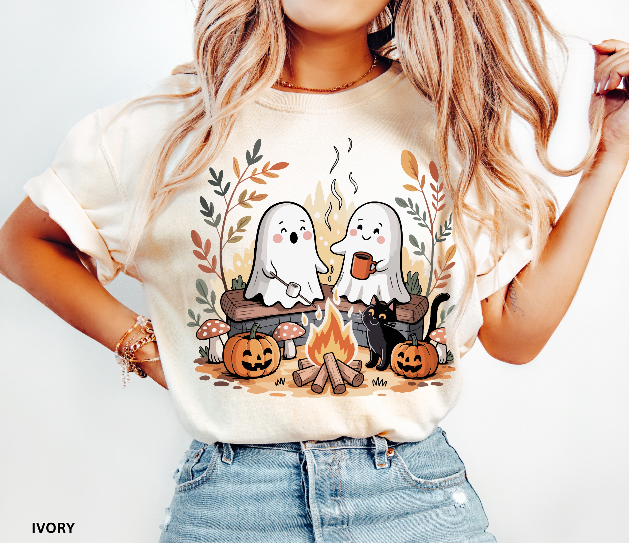 Halloween shirt design featuring two cute ghosts by a campfire, one roasting marshmallows, one holding cocoa, with pumpkins, mushrooms, fall leaves, and a black cat.