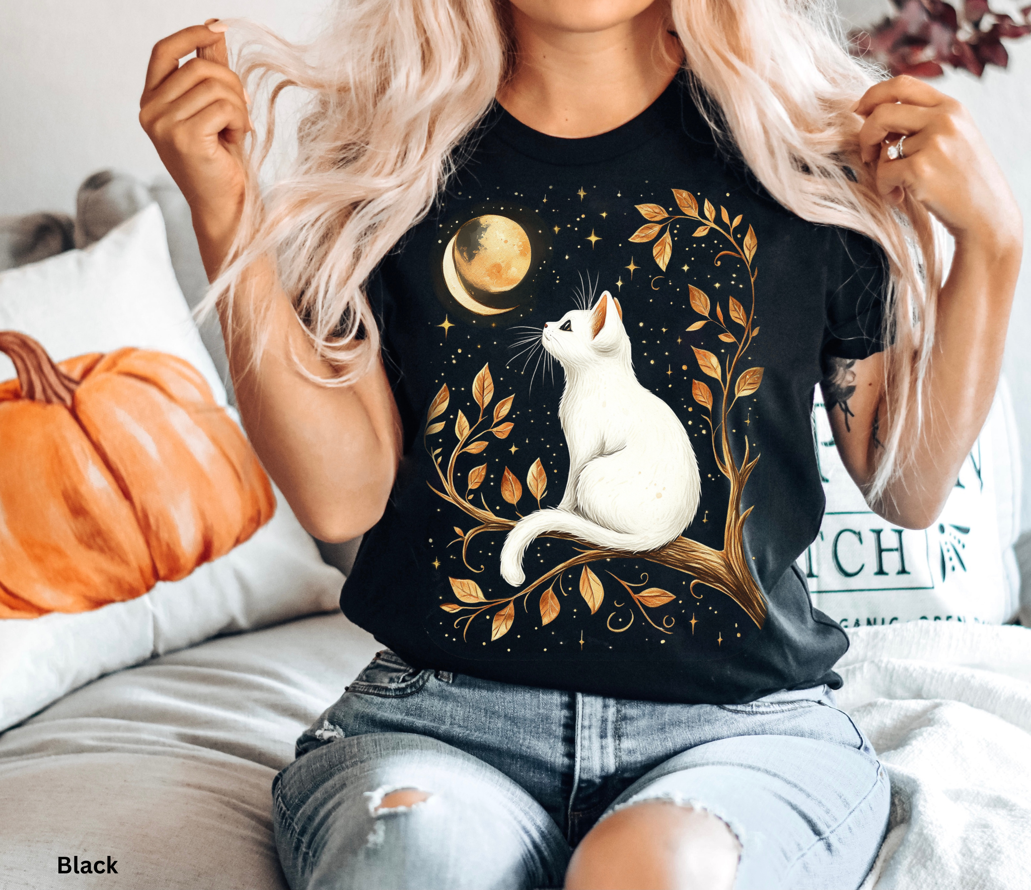 Mystical shirt design featuring a white cat sitting on a golden tree branch, gazing at a crescent moon against a starry night sky.