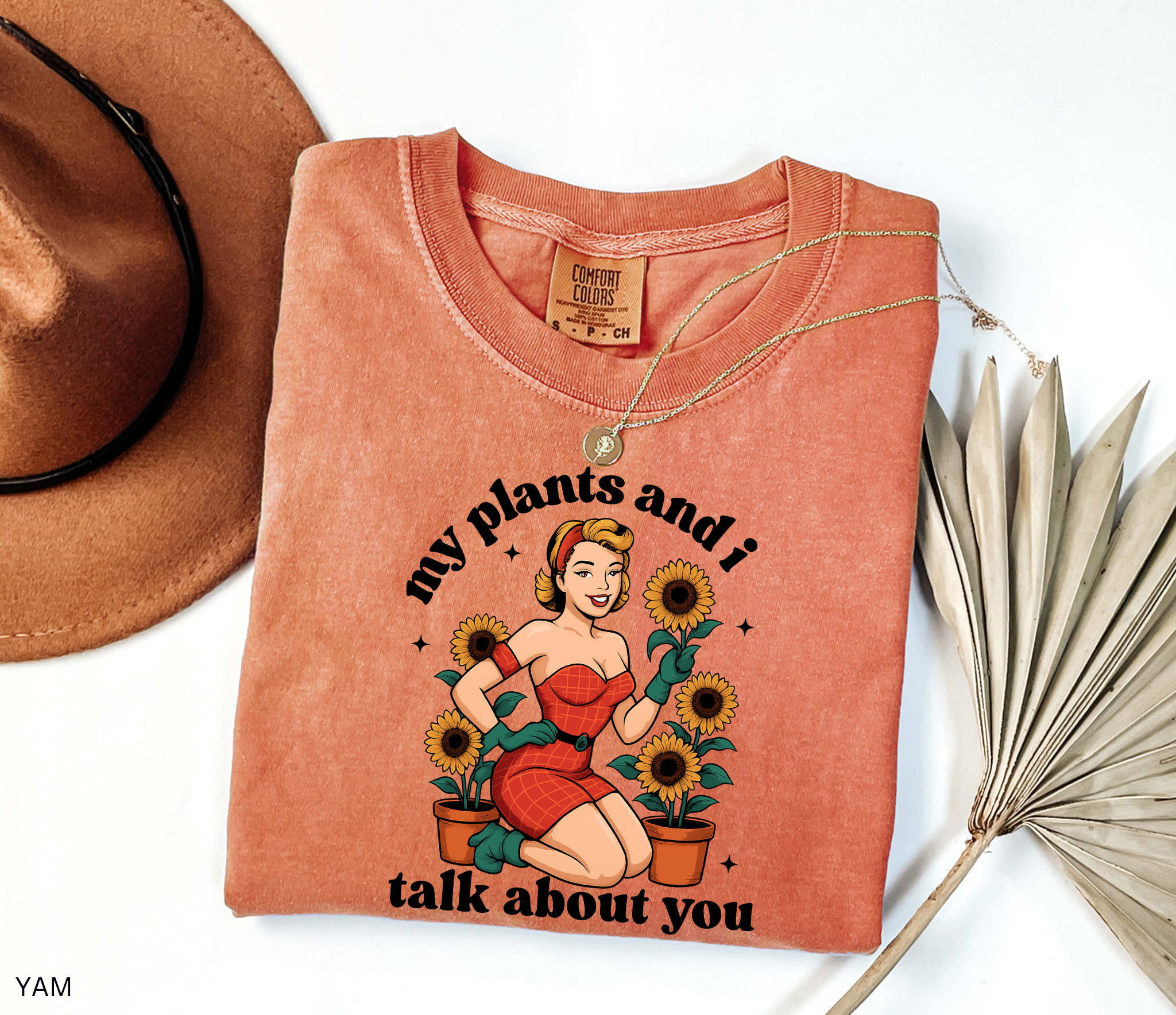 Vintage pin-up style illustration of a glamorous woman in a red dress surrounded by potted sunflowers, printed on a retro gardening t-shirt.