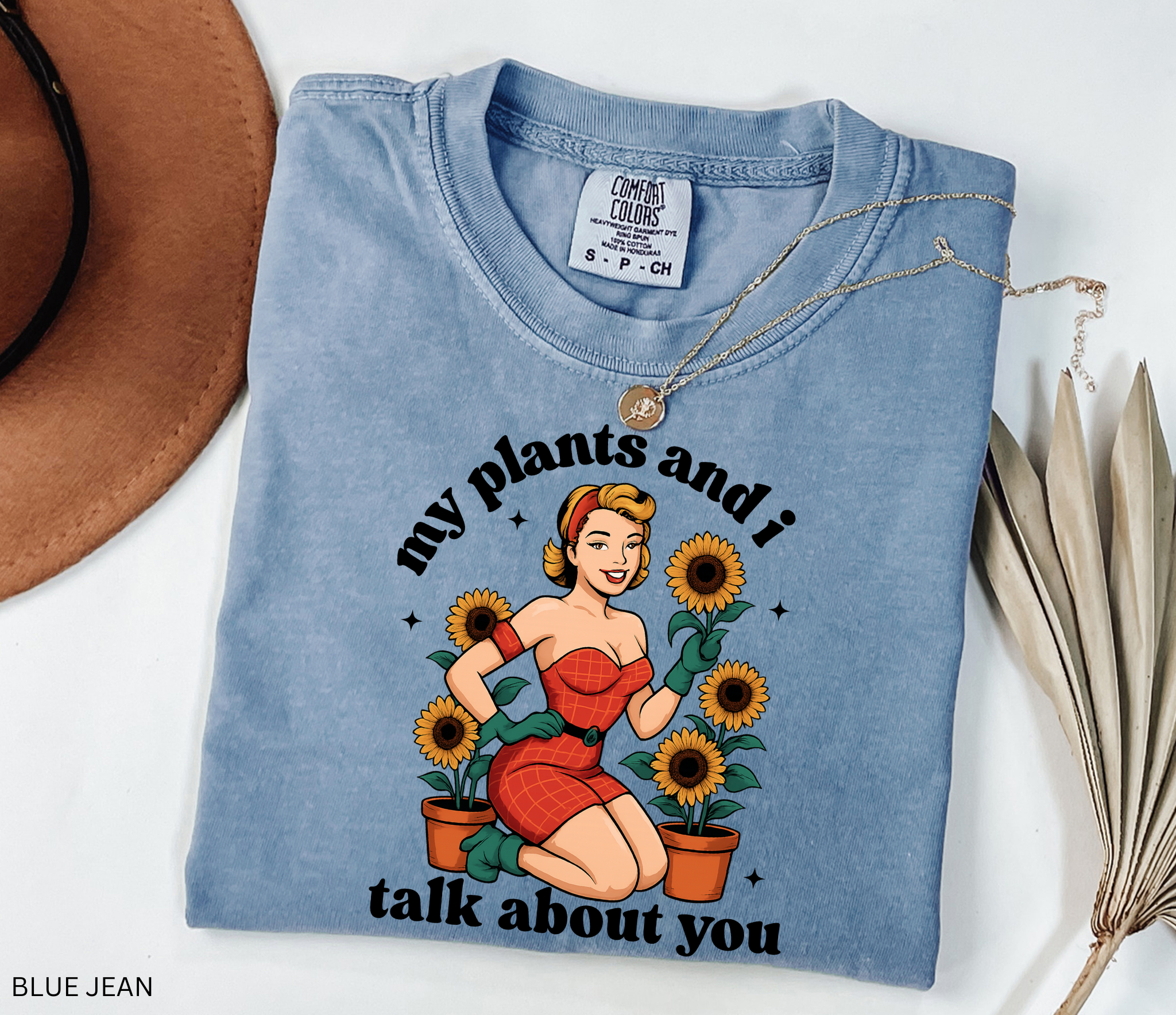 Vintage pin-up style illustration of a glamorous woman in a red dress surrounded by potted sunflowers, printed on a retro gardening t-shirt.