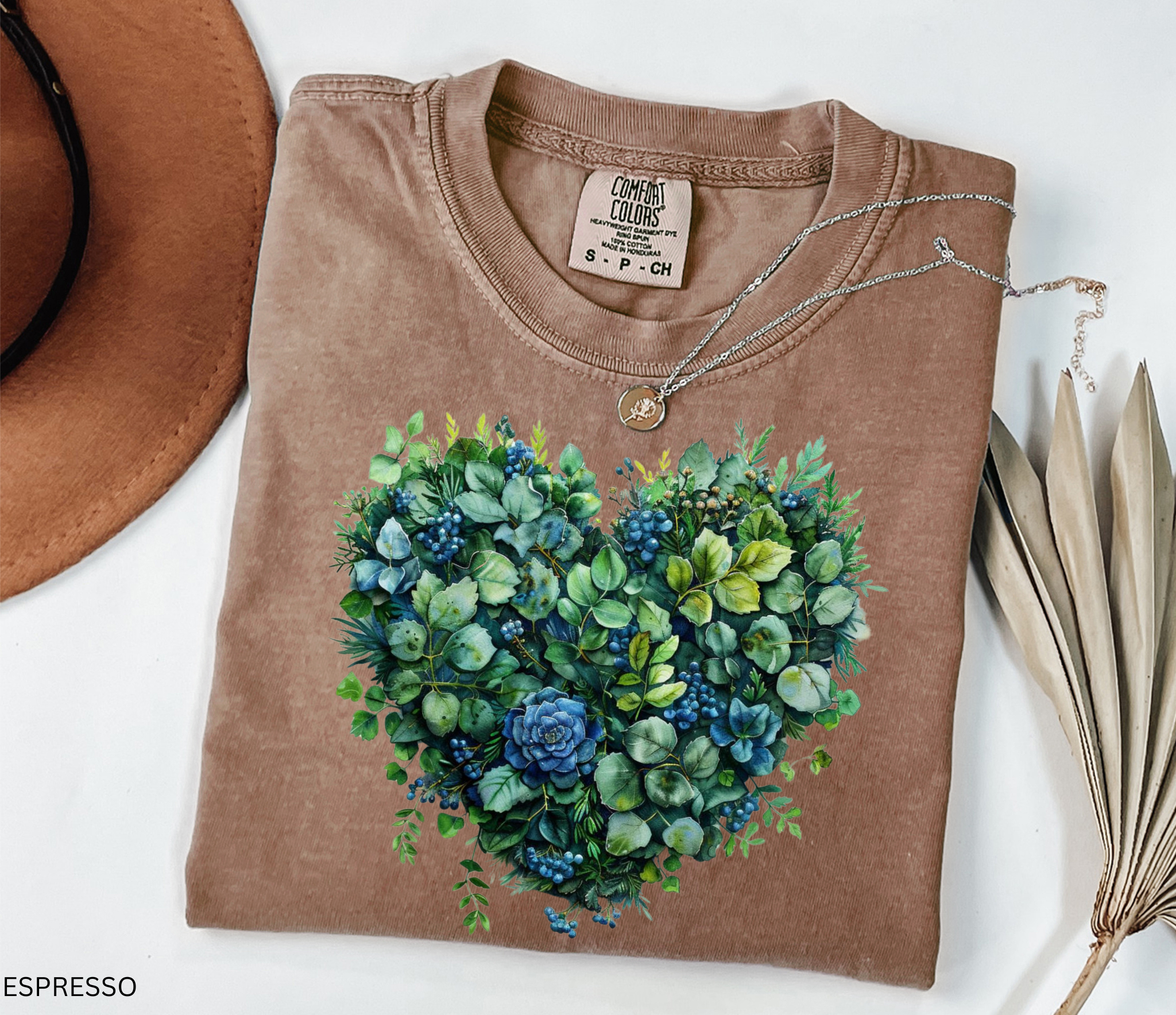 Watercolor-style greenery and succulents arranged in the shape of a heart with blue accents, printed on a cottagecore botanical t-shirt.