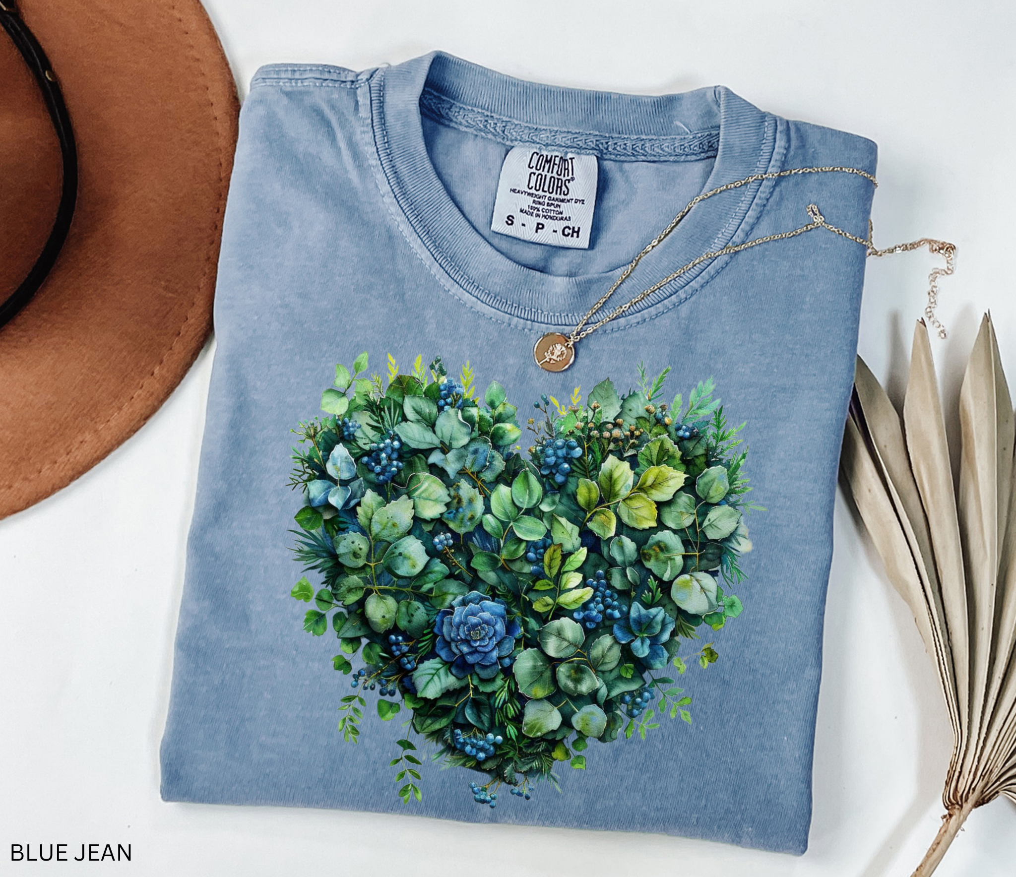 Watercolor-style greenery and succulents arranged in the shape of a heart with blue accents, printed on a cottagecore botanical t-shirt.