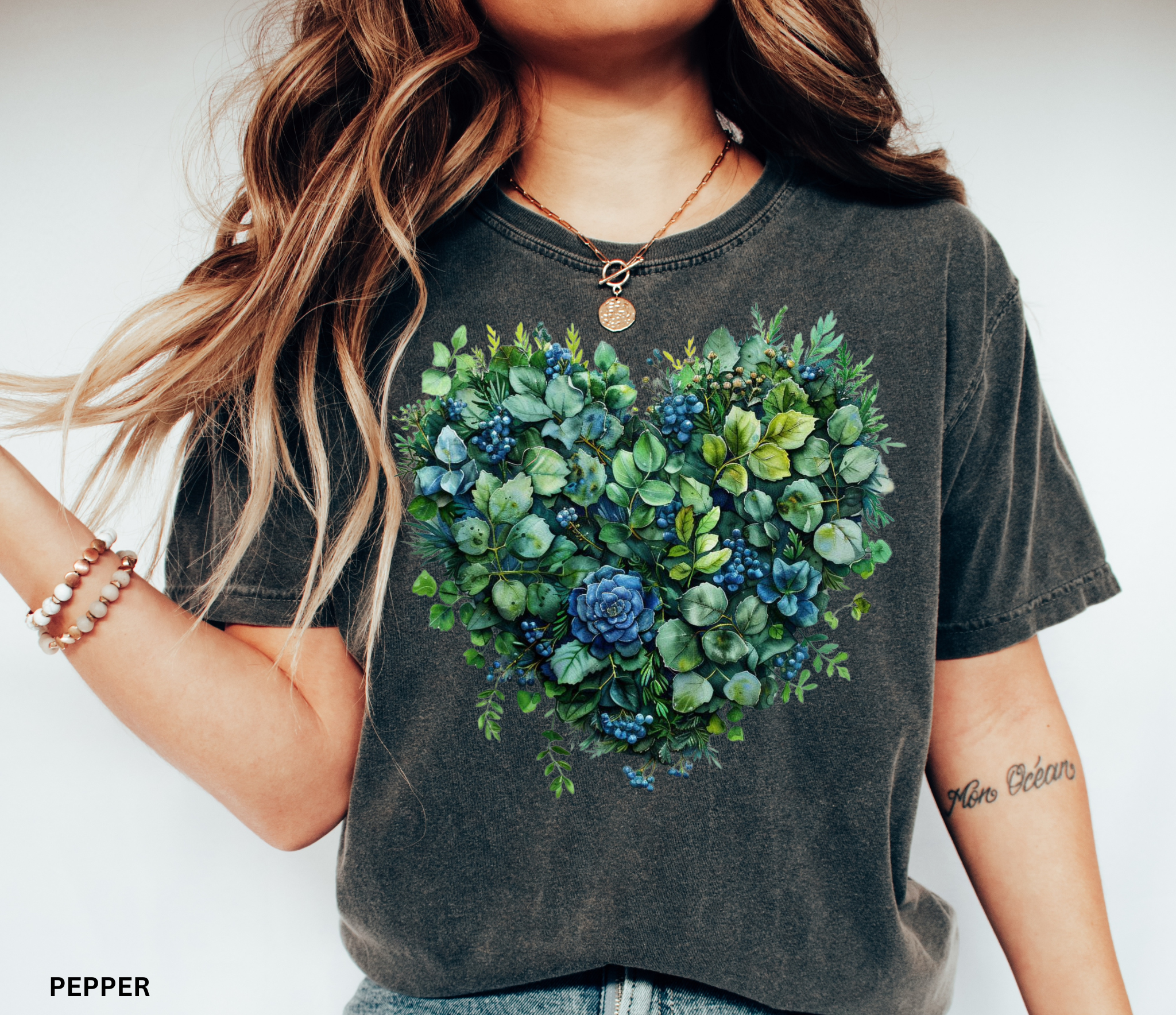 Watercolor-style greenery and succulents arranged in the shape of a heart with blue accents, printed on a cottagecore botanical t-shirt.