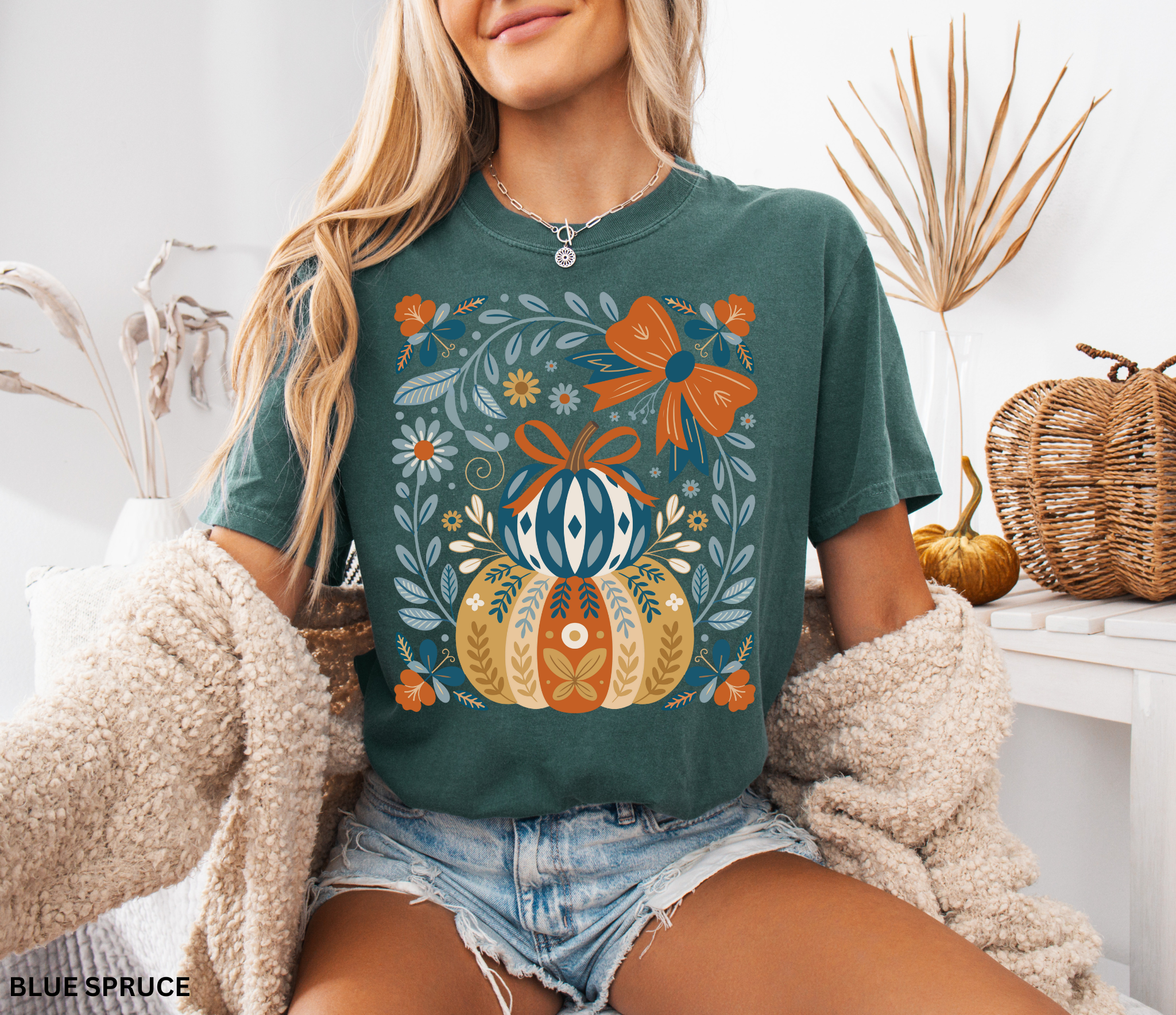 Whimsical folk art pumpkin with bow and floral details in warm autumn colors, printed as a cottagecore fall design on a t-shirt.