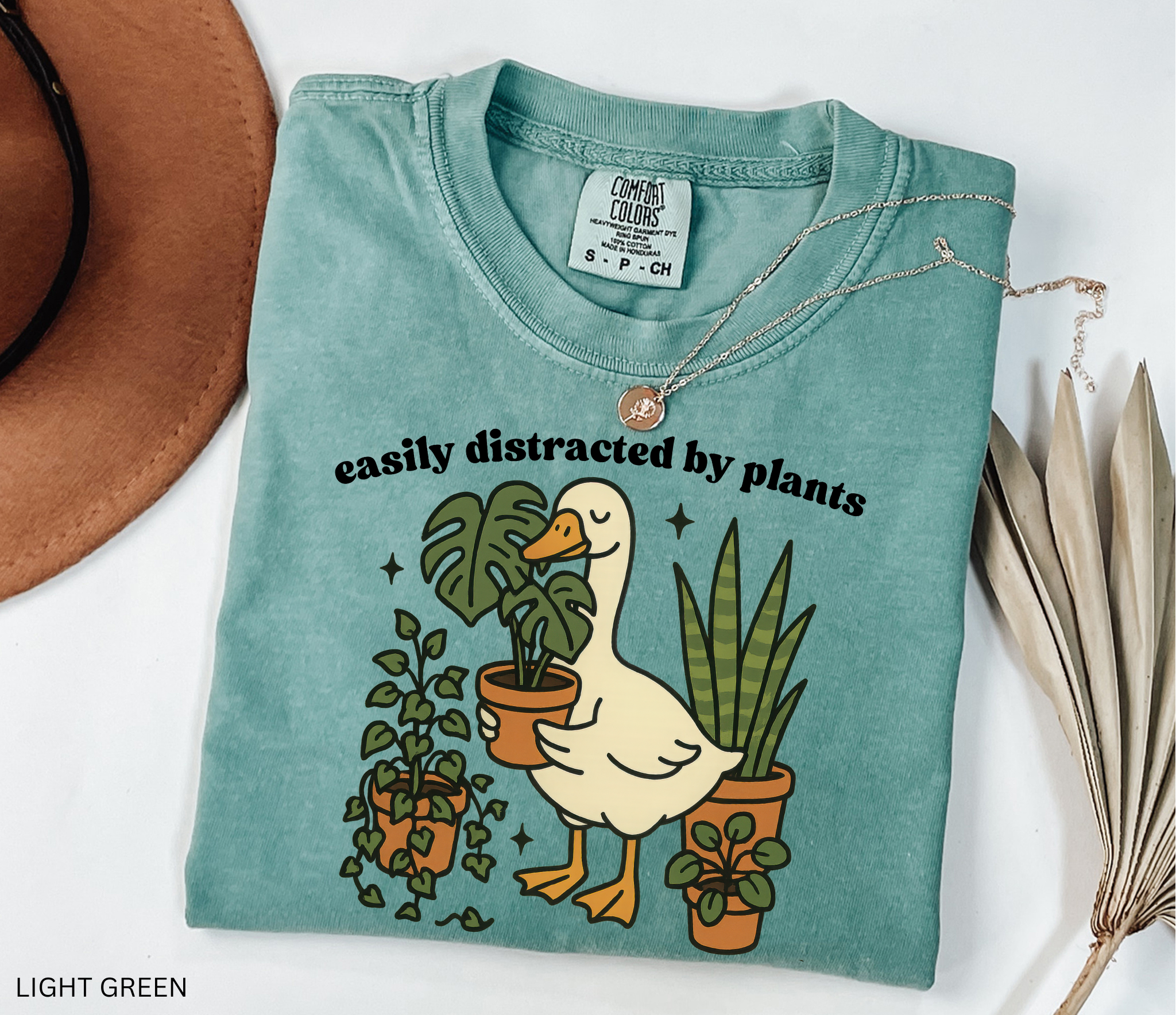 Illustration of a goose holding a monstera plant, surrounded by potted greenery including ivy, snake plants, and succulents.