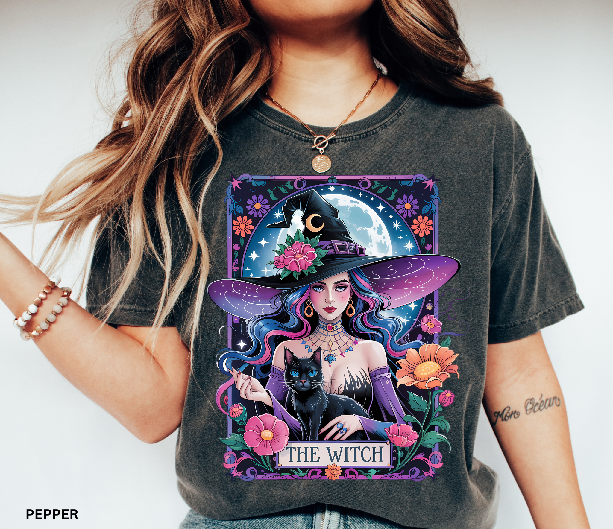 Illustration of a mystical witch with flowing hair, moonlit background, black cat, and floral celestial details on a Halloween shirt.