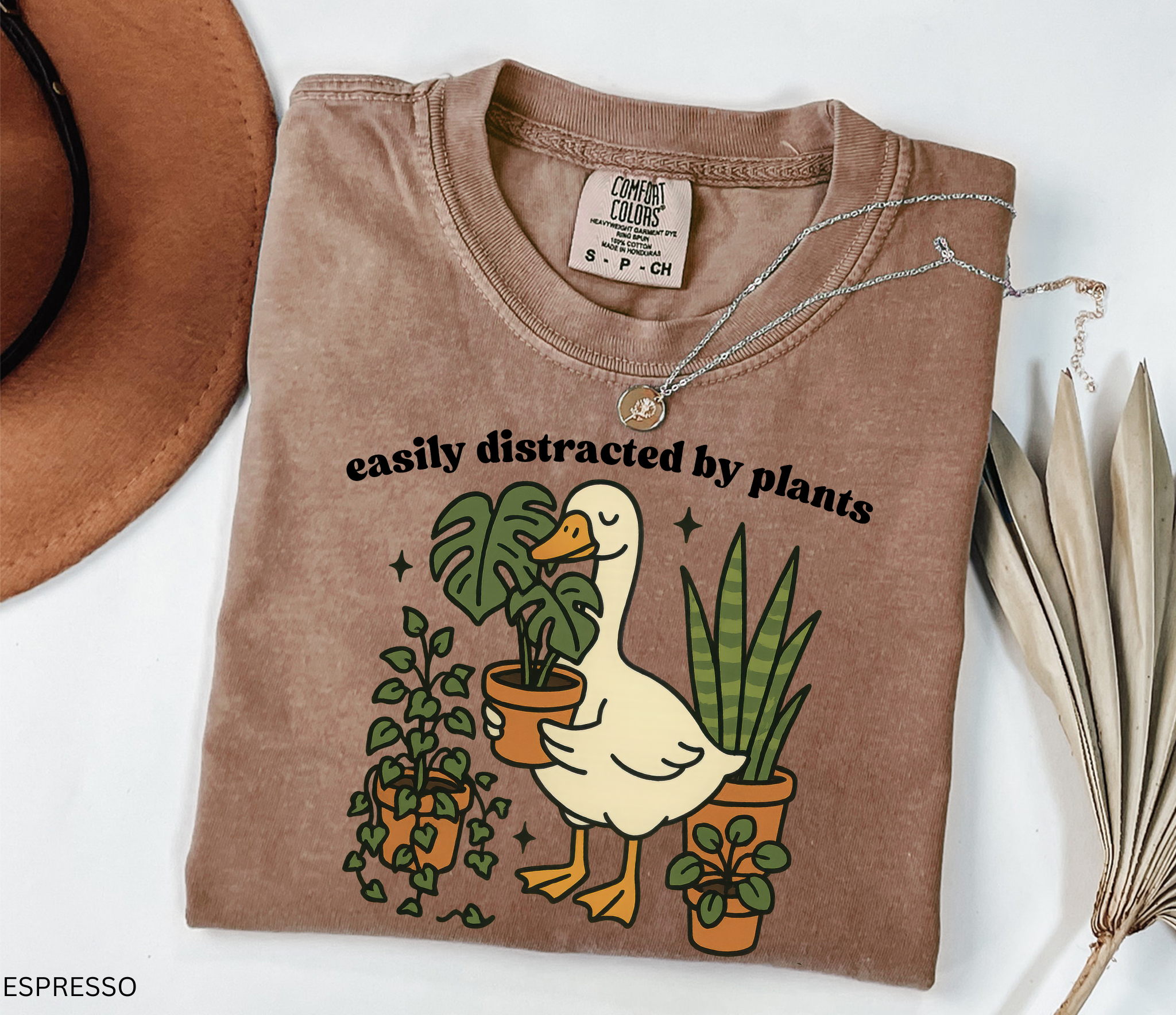 Illustration of a goose holding a monstera plant, surrounded by potted greenery including ivy, snake plants, and succulents.