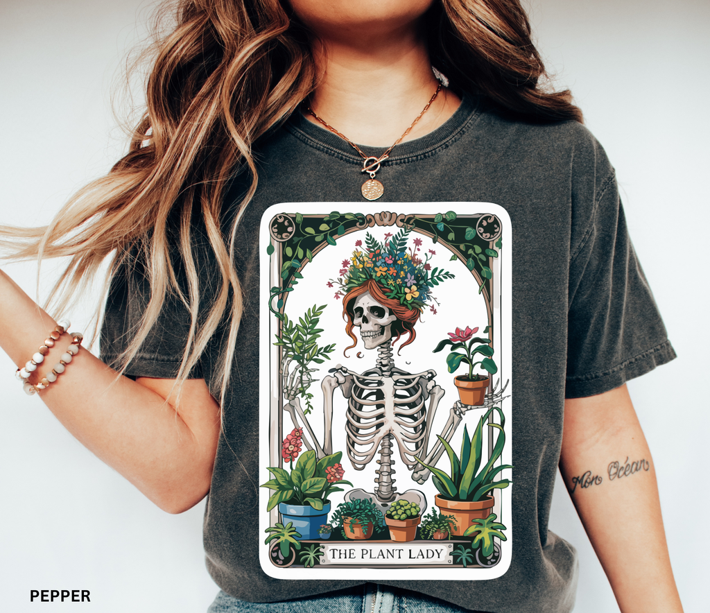 Floral-crowned skeleton holding potted plants, surrounded by greenery — witchy botanical “The Plant Lady” shirt design, cottagecore aesthetic.