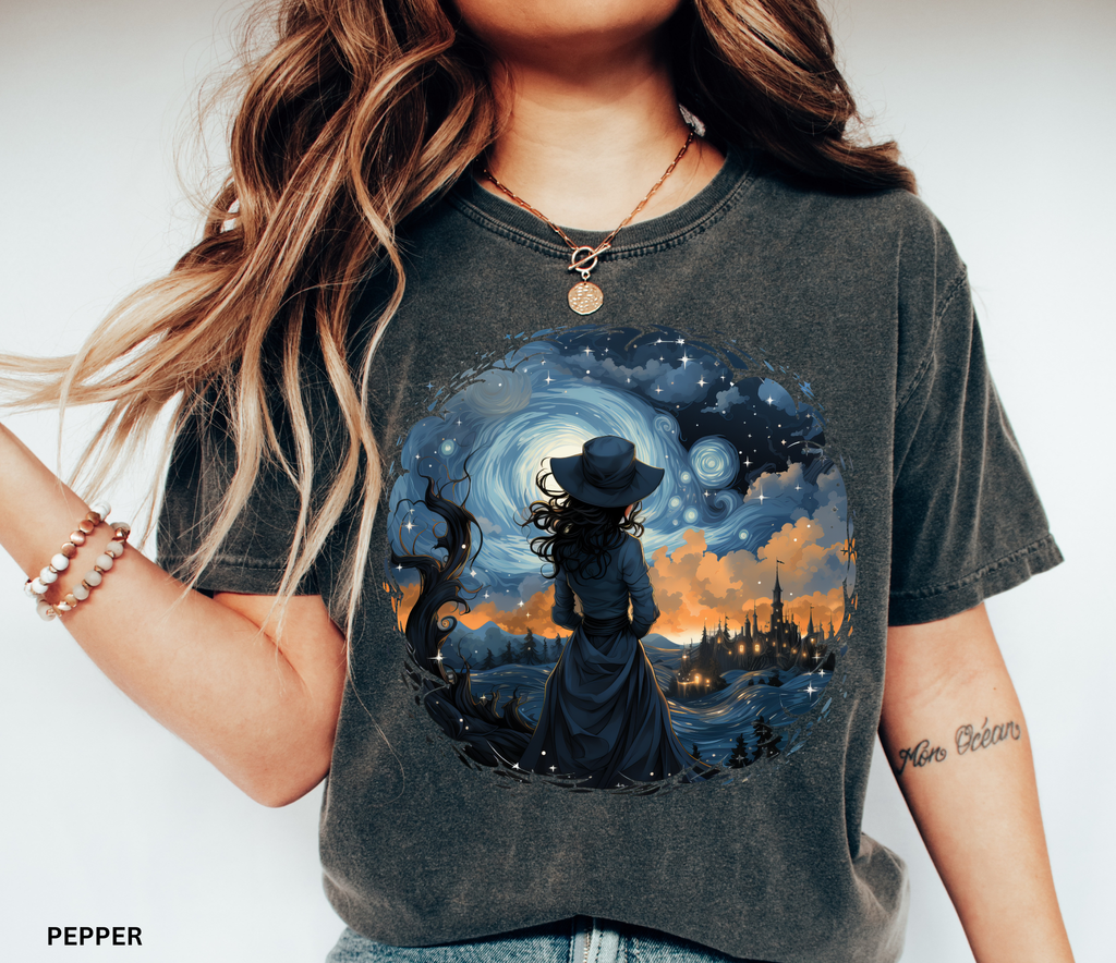 Celestial witch standing beneath swirling galaxy and glowing town – witchcore aesthetic shirt design