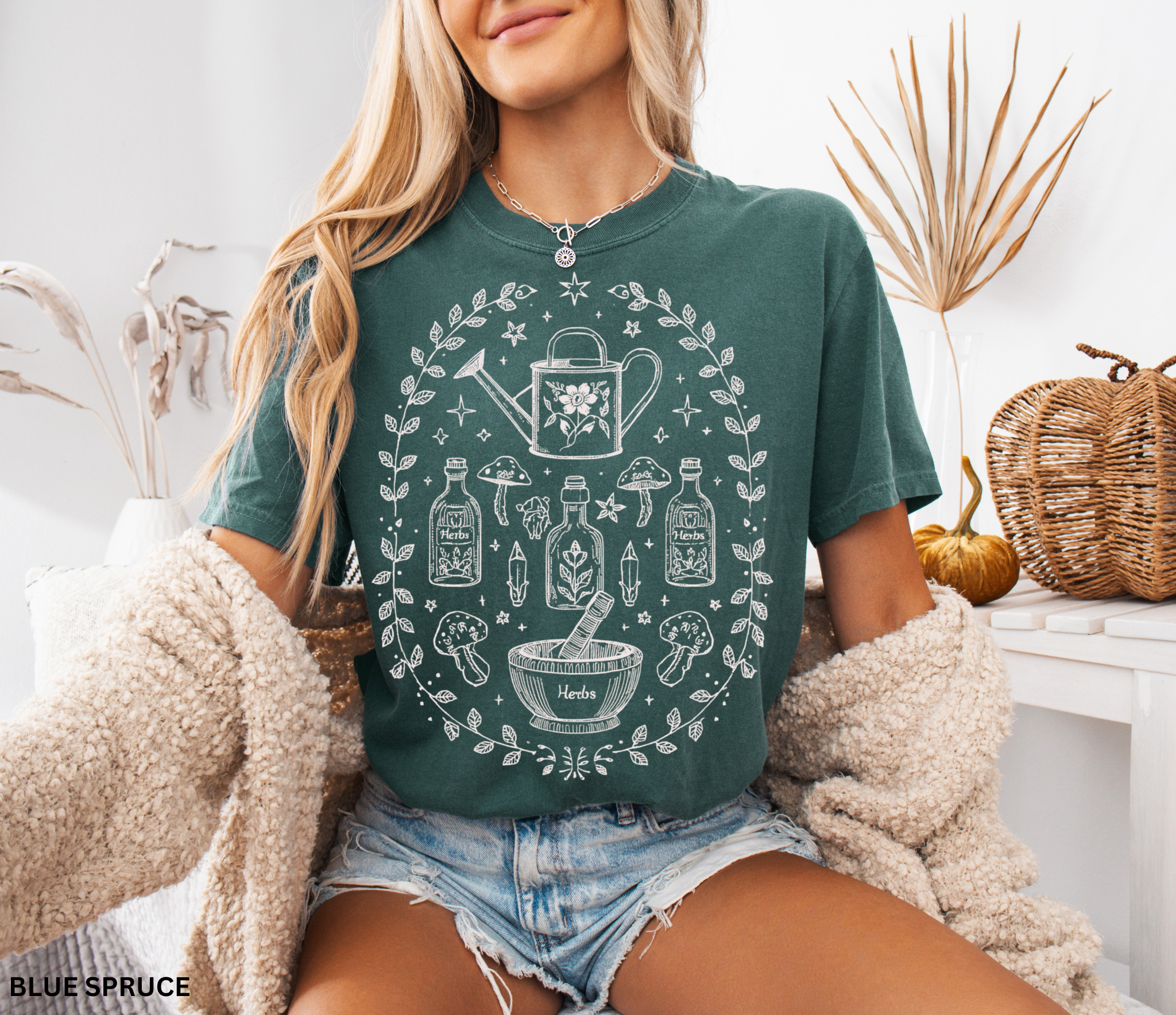 Hand-drawn botanical witch t-shirt featuring vintage herb bottles, mushrooms, crystals, and watering can – mystical garden witch aesthetic design on Comfort Colors tee.