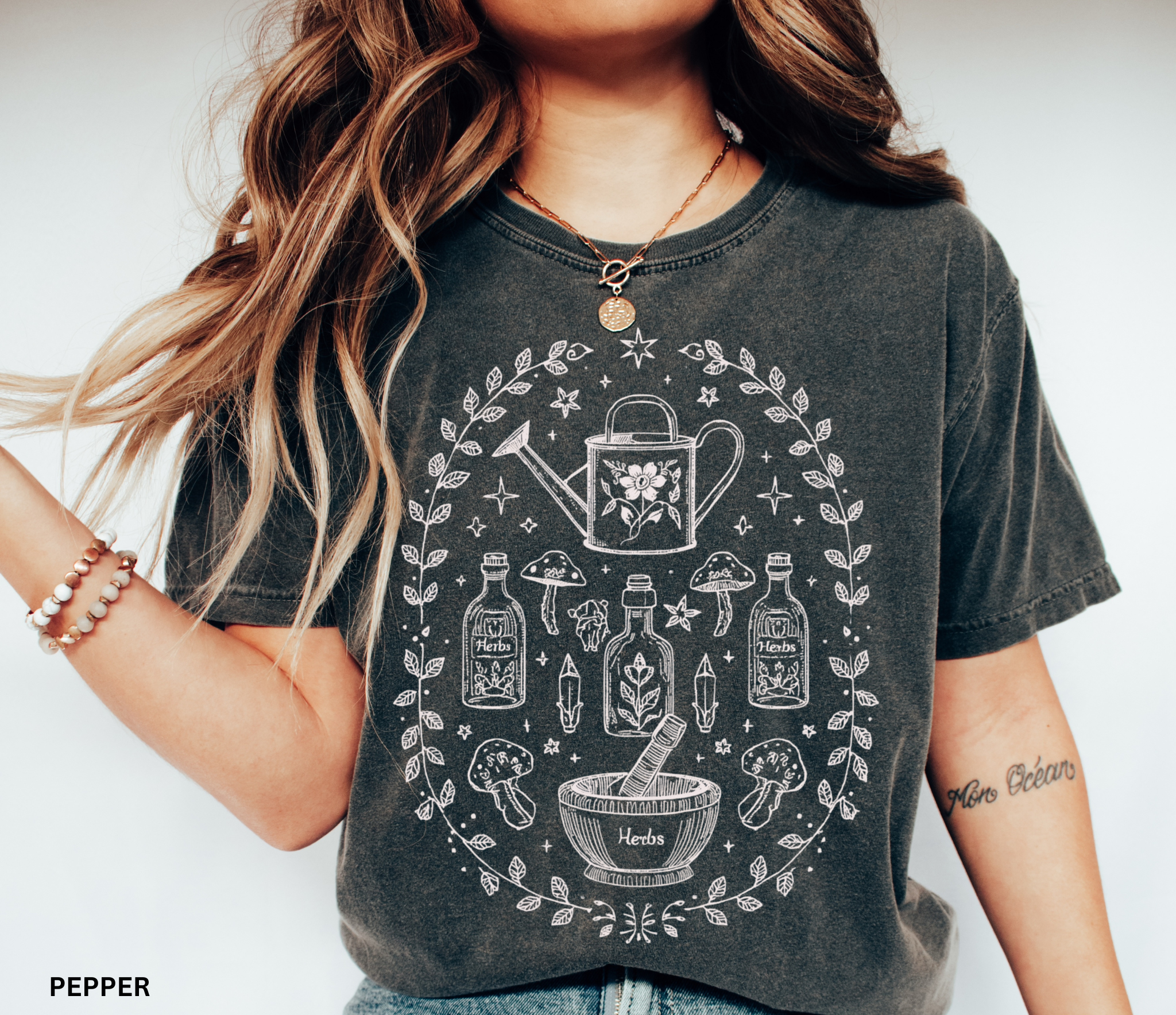 Hand-drawn botanical witch t-shirt featuring vintage herb bottles, mushrooms, crystals, and watering can – mystical garden witch aesthetic design on Comfort Colors tee.