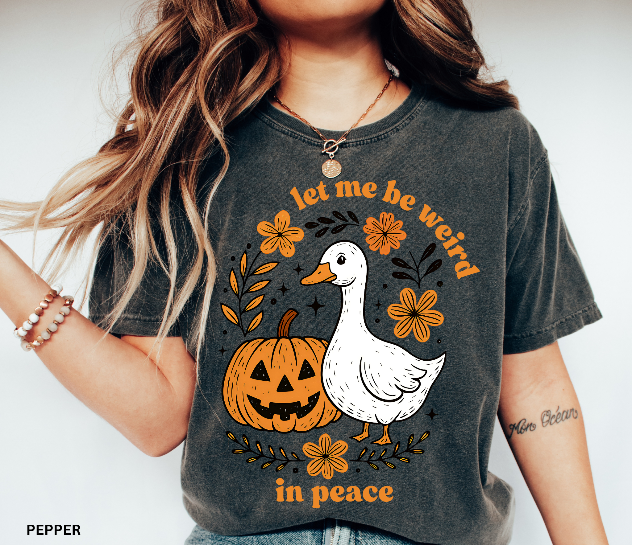 Funny Halloween goose t-shirt featuring “Let Me Be Weird in Peace” text, pumpkin, and flowers — cottagecore fall aesthetic design on Comfort Colors shirt.