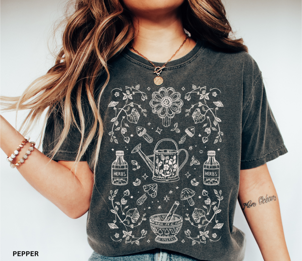 Hand-drawn herbal apothecary t-shirt featuring vintage bottles, mushrooms, watering can, and mortar and pestle — botanical witch aesthetic on Comfort Colors shirt.