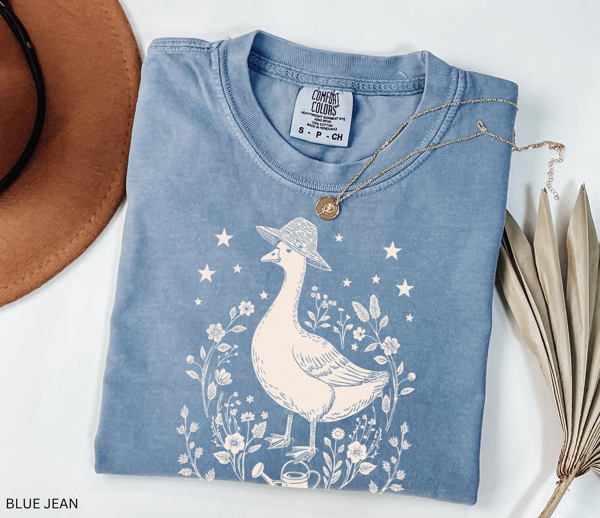 Cottagecore goose wearing hat surrounded by flowers and stars — vintage garden design printed on soft Comfort Colors shirt.