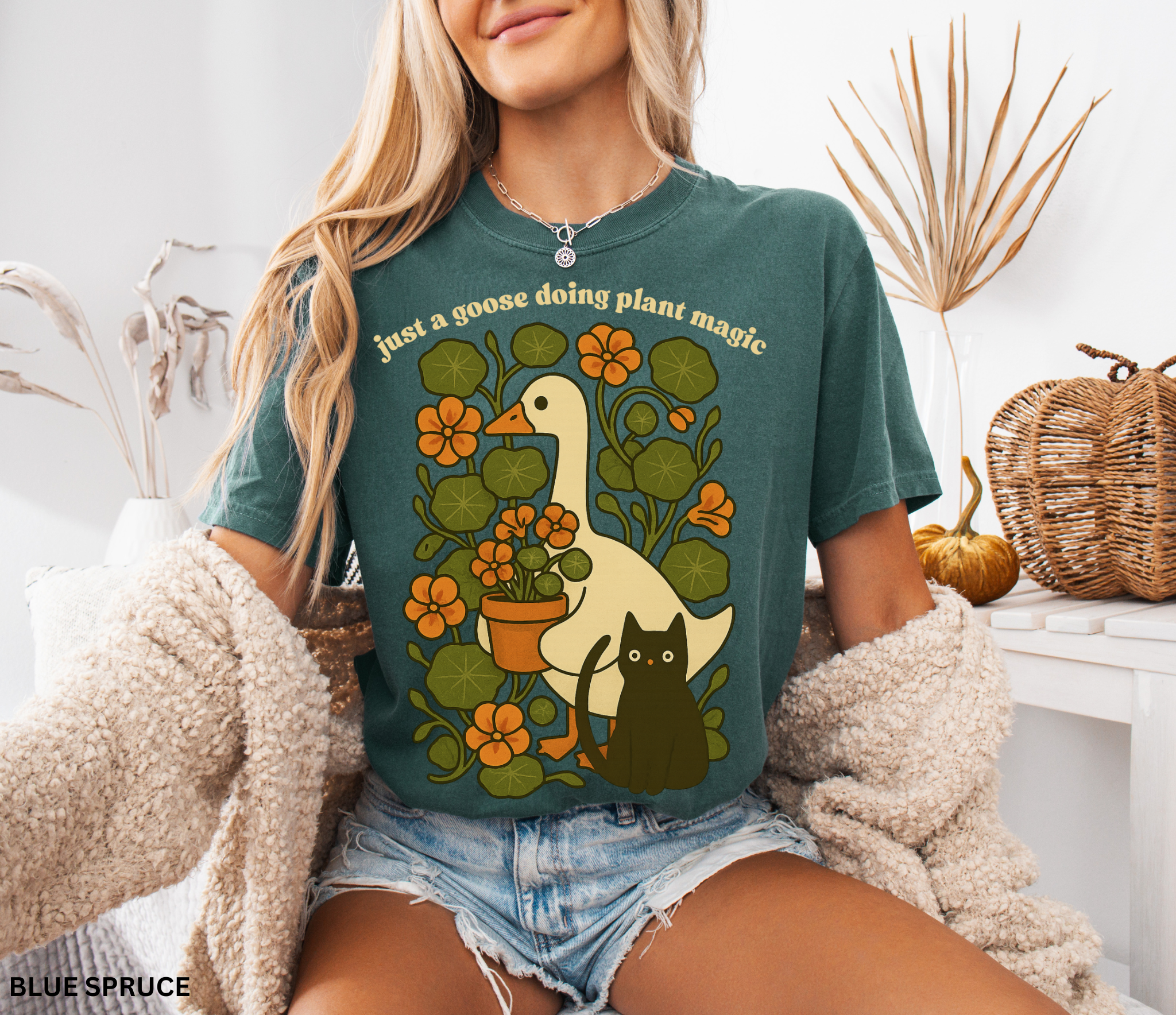 Goose holding a pot of nasturtiums with black cat among orange flowers — cozy cottagecore witchy plant lover shirt.