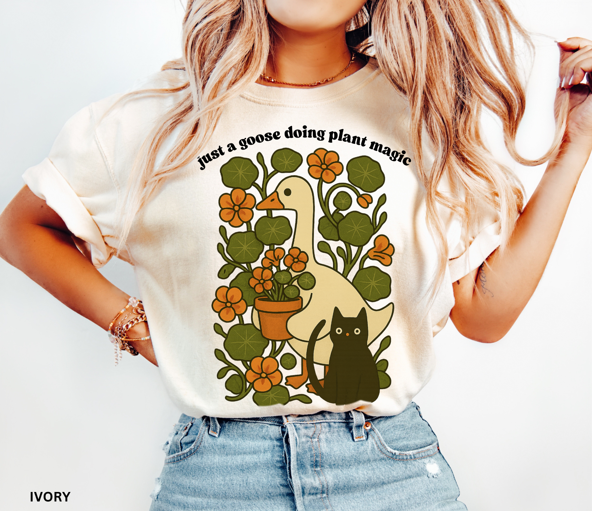 Goose holding a pot of nasturtiums with black cat among orange flowers — cozy cottagecore witchy plant lover shirt.