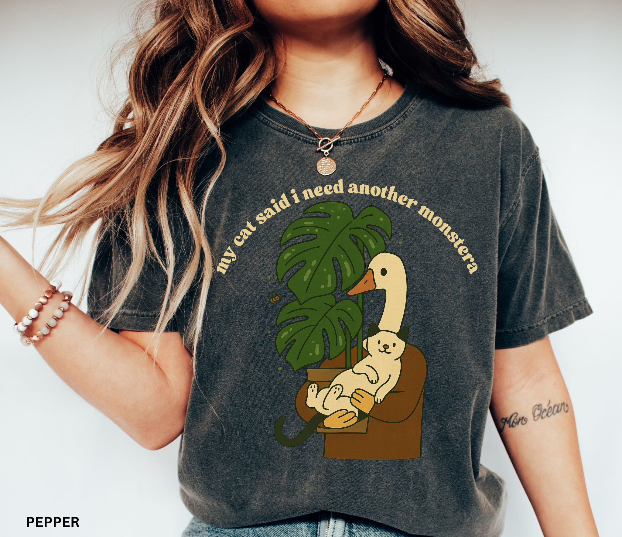 Goose holding a cat beside a monstera plant with the text “My Cat Said I Need Another Monstera” on a Comfort Colors shirt.