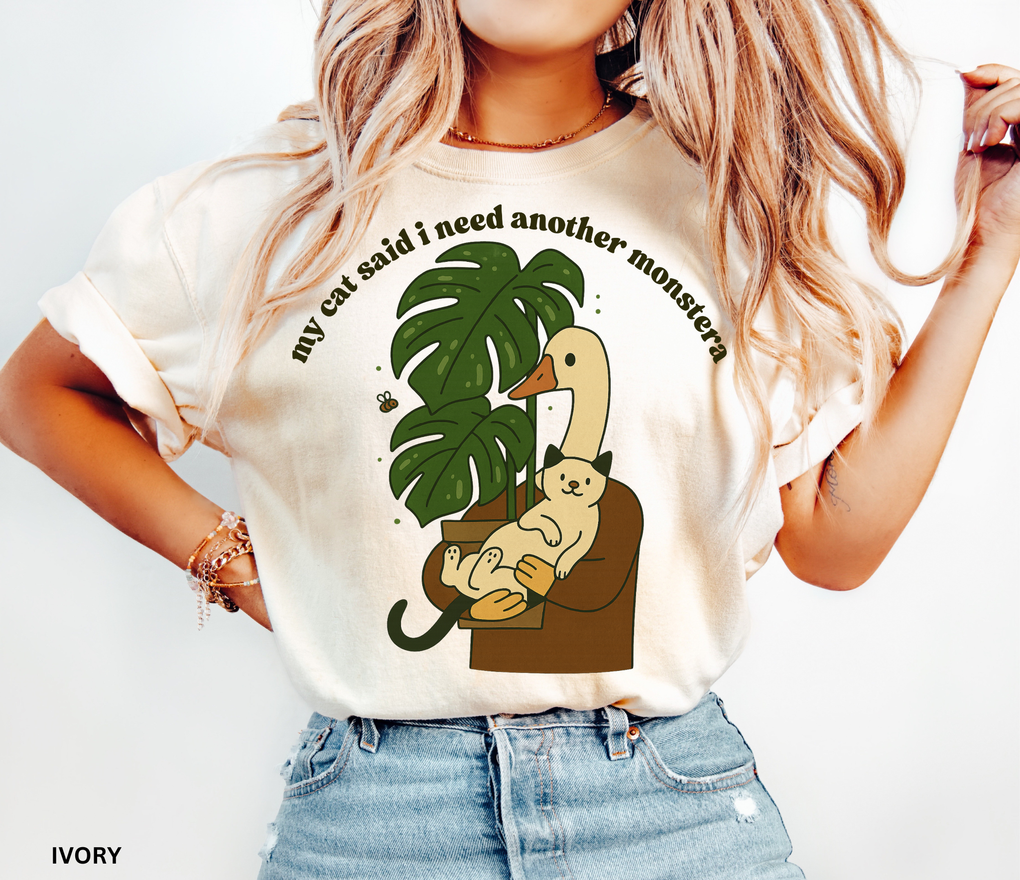 Goose holding a cat beside a monstera plant with the text “My Cat Said I Need Another Monstera” on a Comfort Colors shirt.