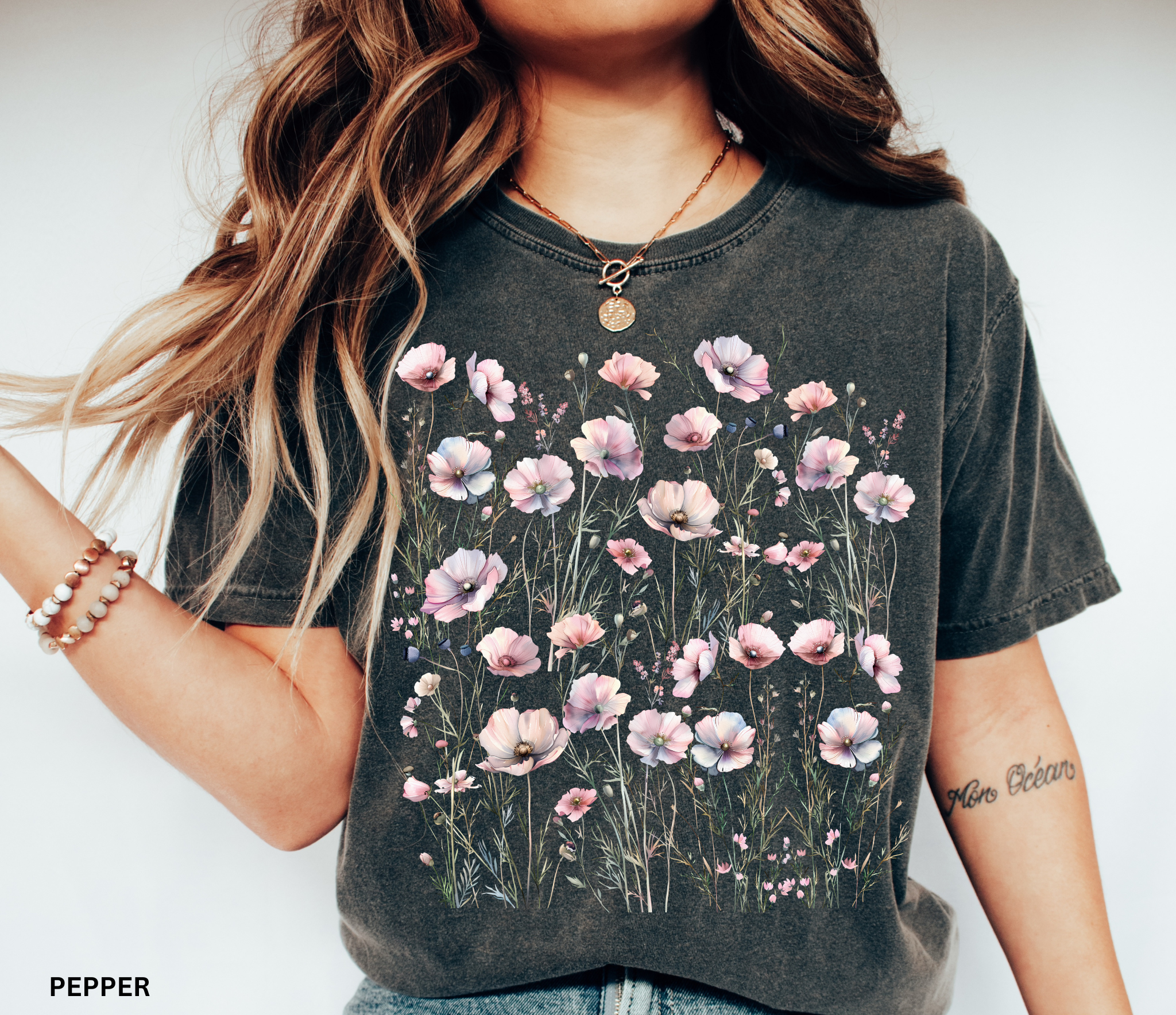 Delicate pastel wildflowers and soft pink blossoms arranged in a meadow pattern on a vintage Comfort Colors cottagecore shirt.