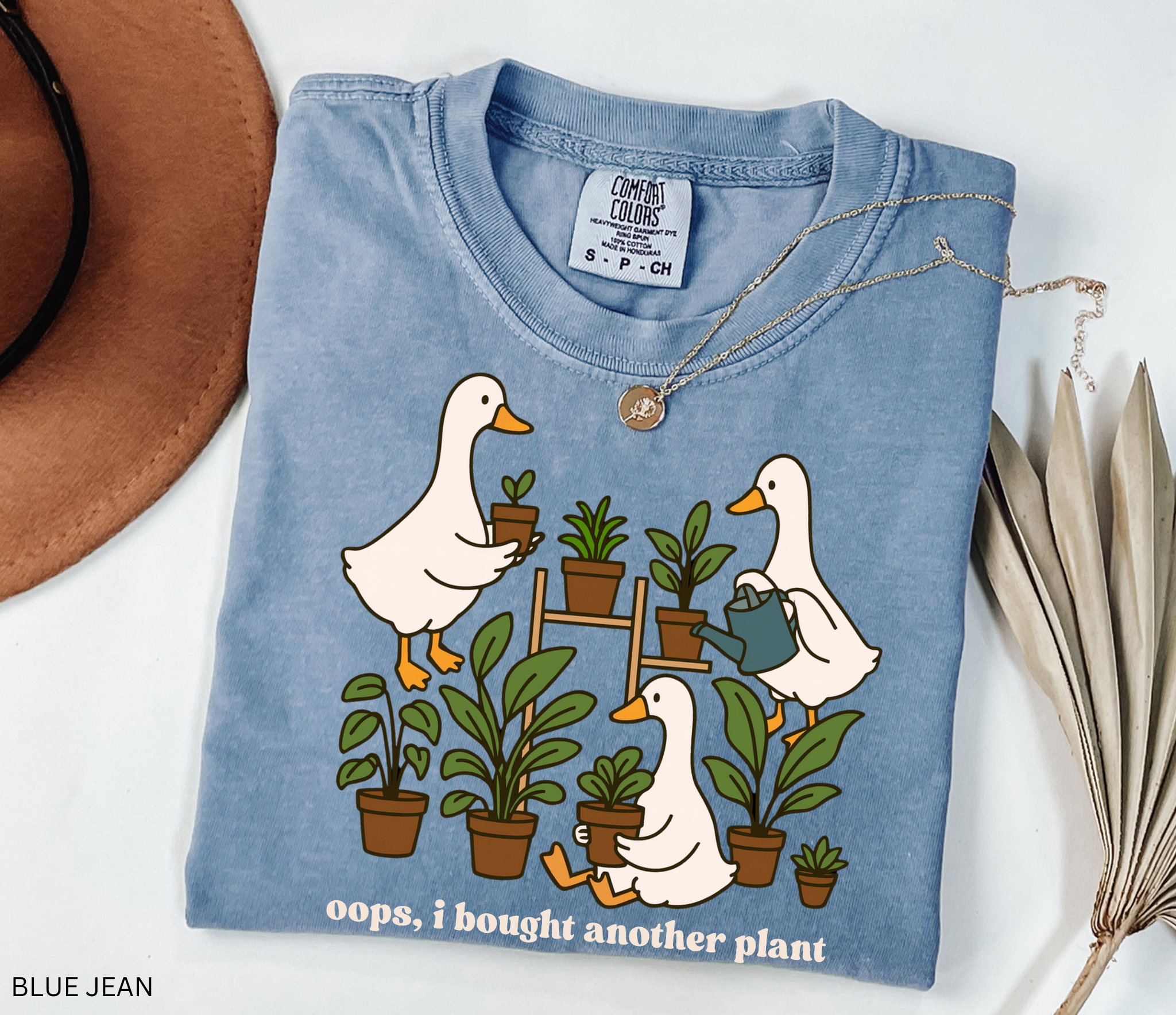 Cute shirt design featuring three geese with potted plants and the quote “Oops, I bought another plant.” Perfect for plant lovers and cottagecore style fans.
