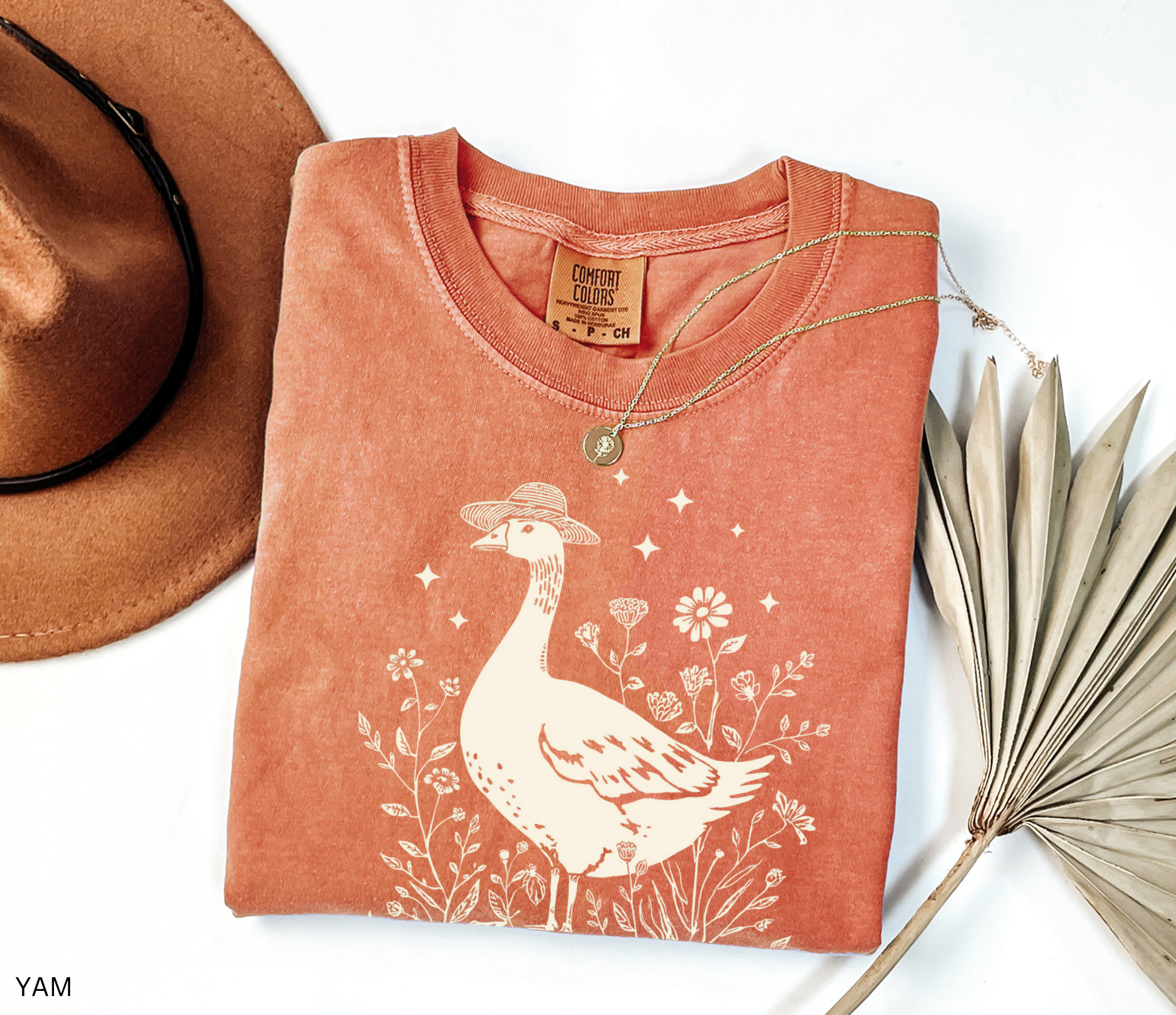 Whimsical goose wearing a straw hat surrounded by flowers and a watering can, cottagecore gardening shirt design.