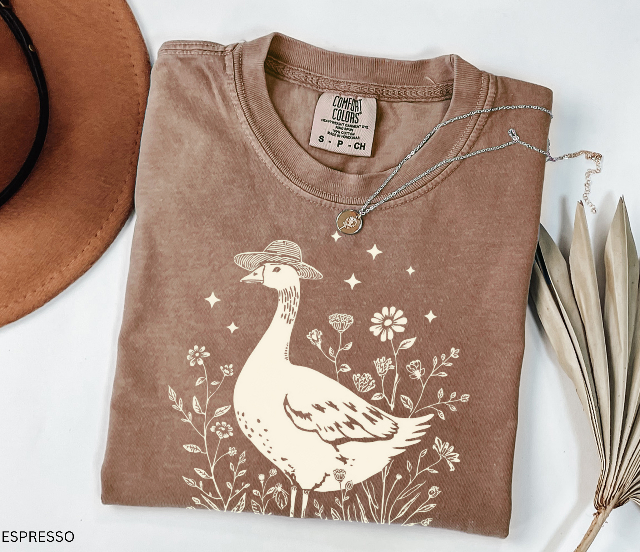 Whimsical goose wearing a straw hat surrounded by flowers and a watering can, cottagecore gardening shirt design.