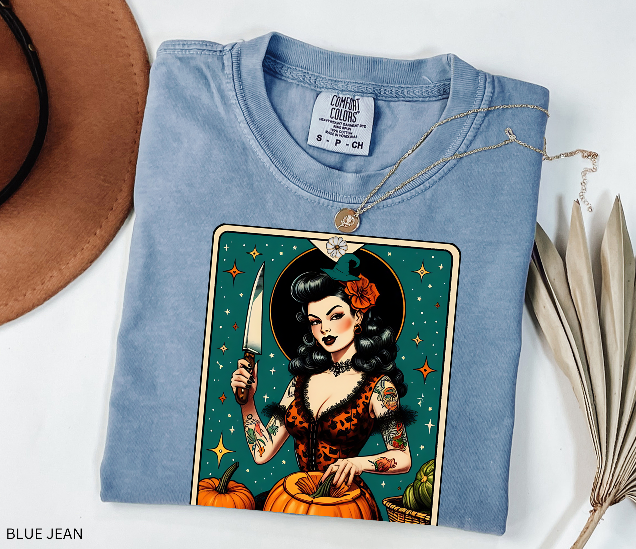 Vintage pin-up witch carving pumpkins under stars in a tarot-style design titled “The Gourd Witch.”