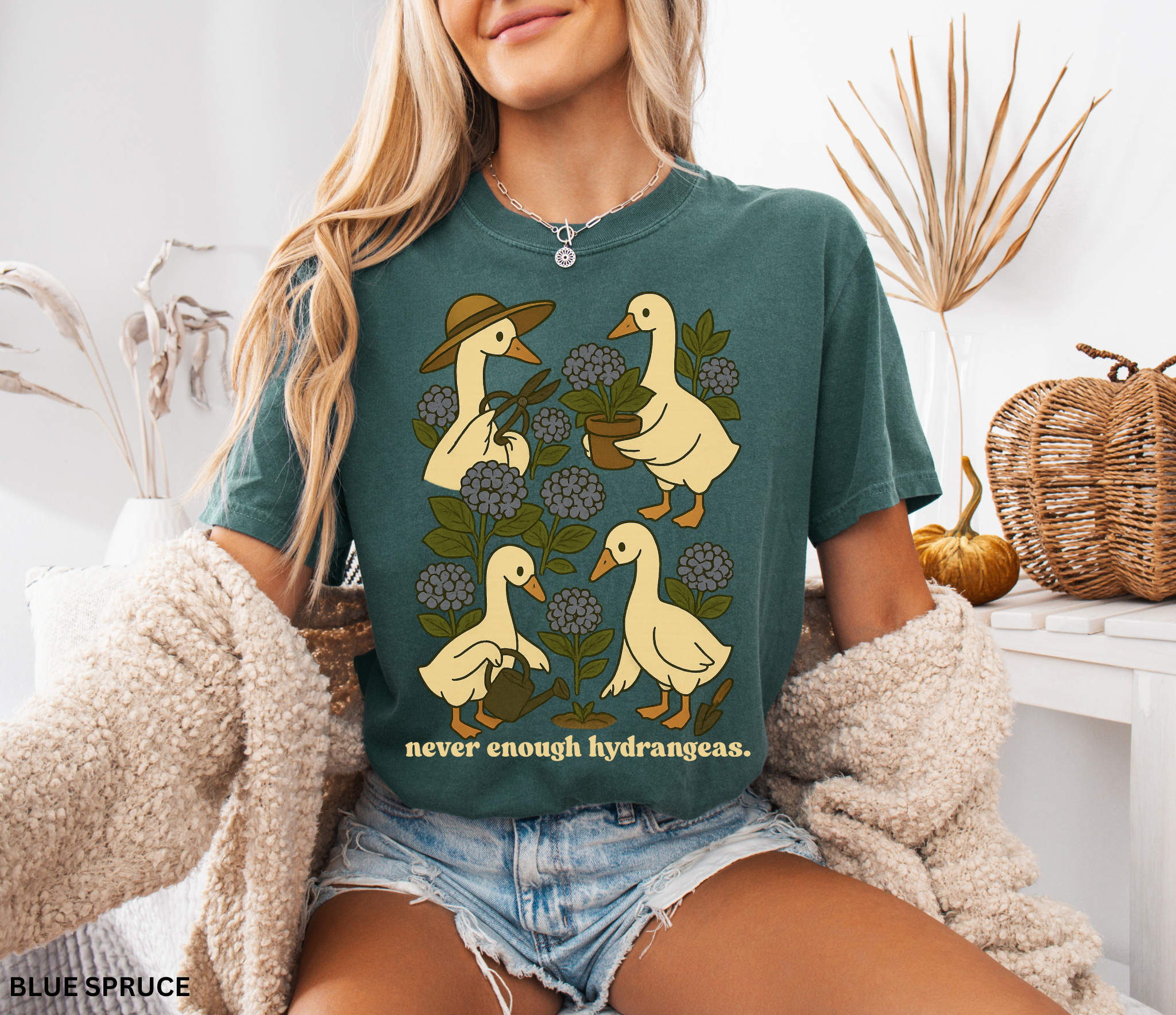 Illustration of four geese gardening among blue hydrangeas with text “never enough hydrangeas.” Cottagecore garden shirt design.