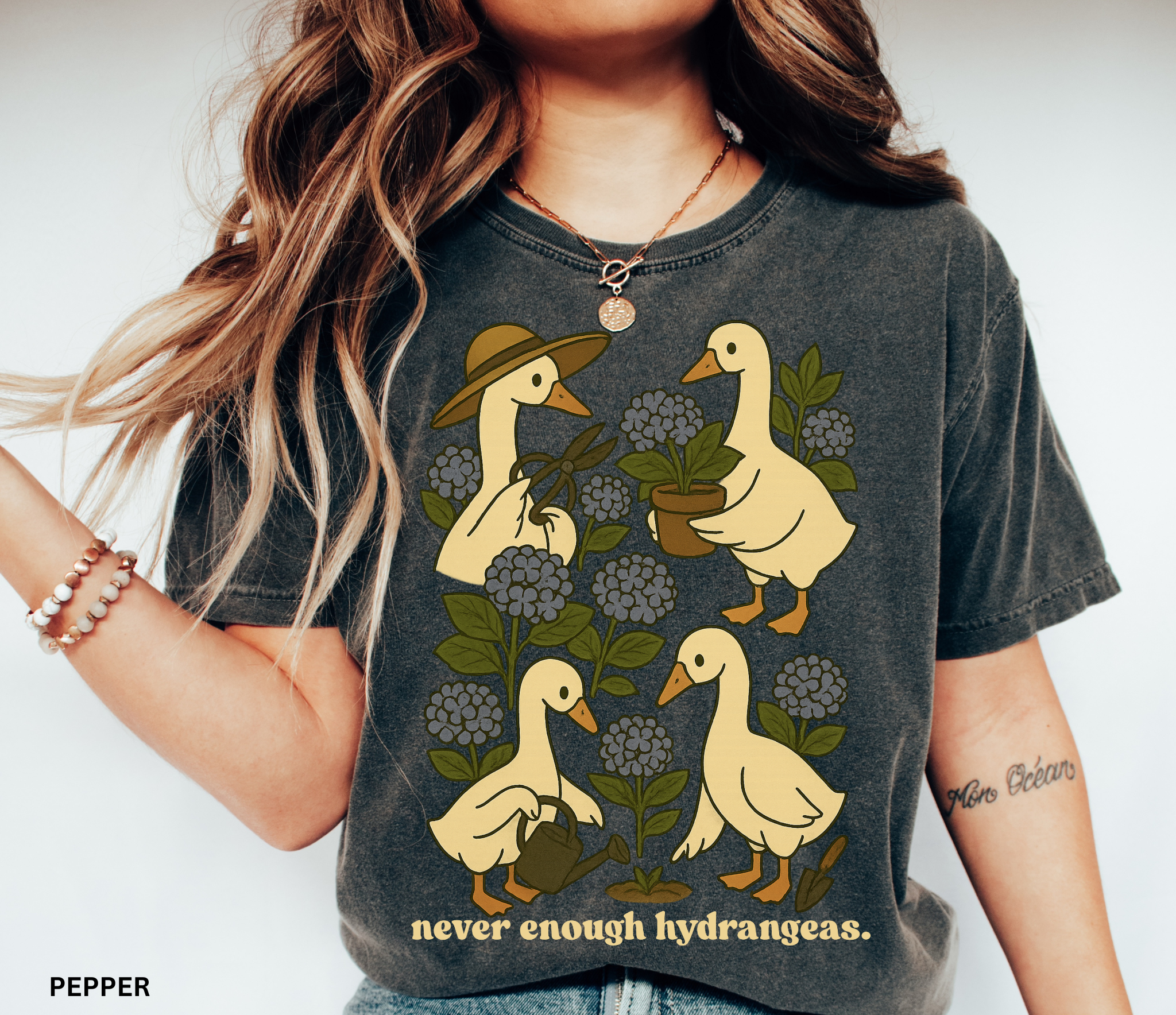 Illustration of four geese gardening among blue hydrangeas with text “never enough hydrangeas.” Cottagecore garden shirt design.