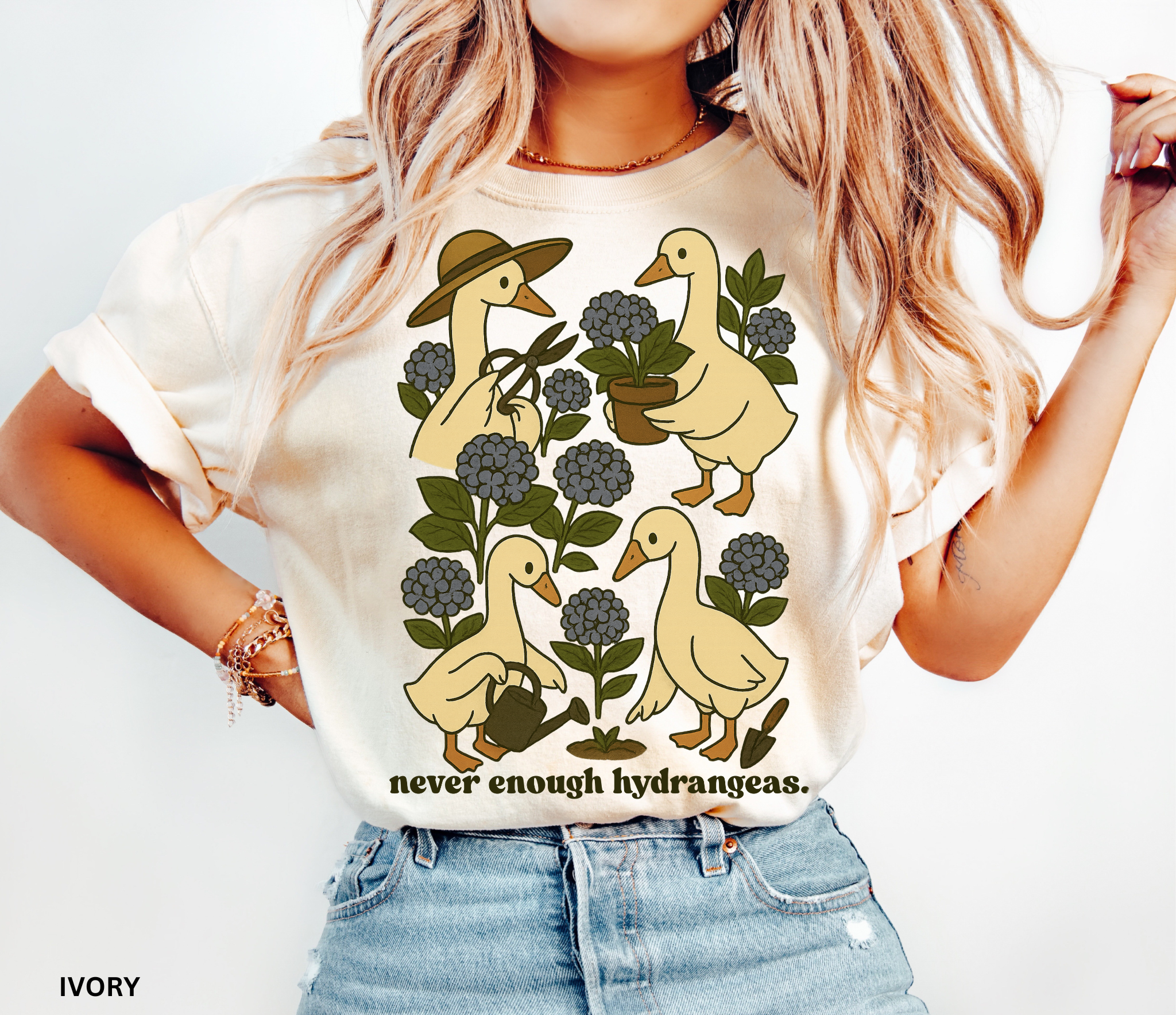 Illustration of four geese gardening among blue hydrangeas with text “never enough hydrangeas.” Cottagecore garden shirt design.