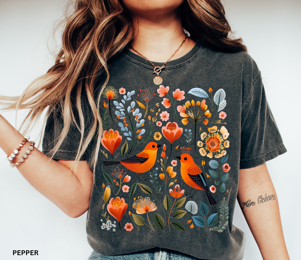 Scandinavian folk art design with two orange songbirds surrounded by blue and orange flowers in a Nordic floral pattern.