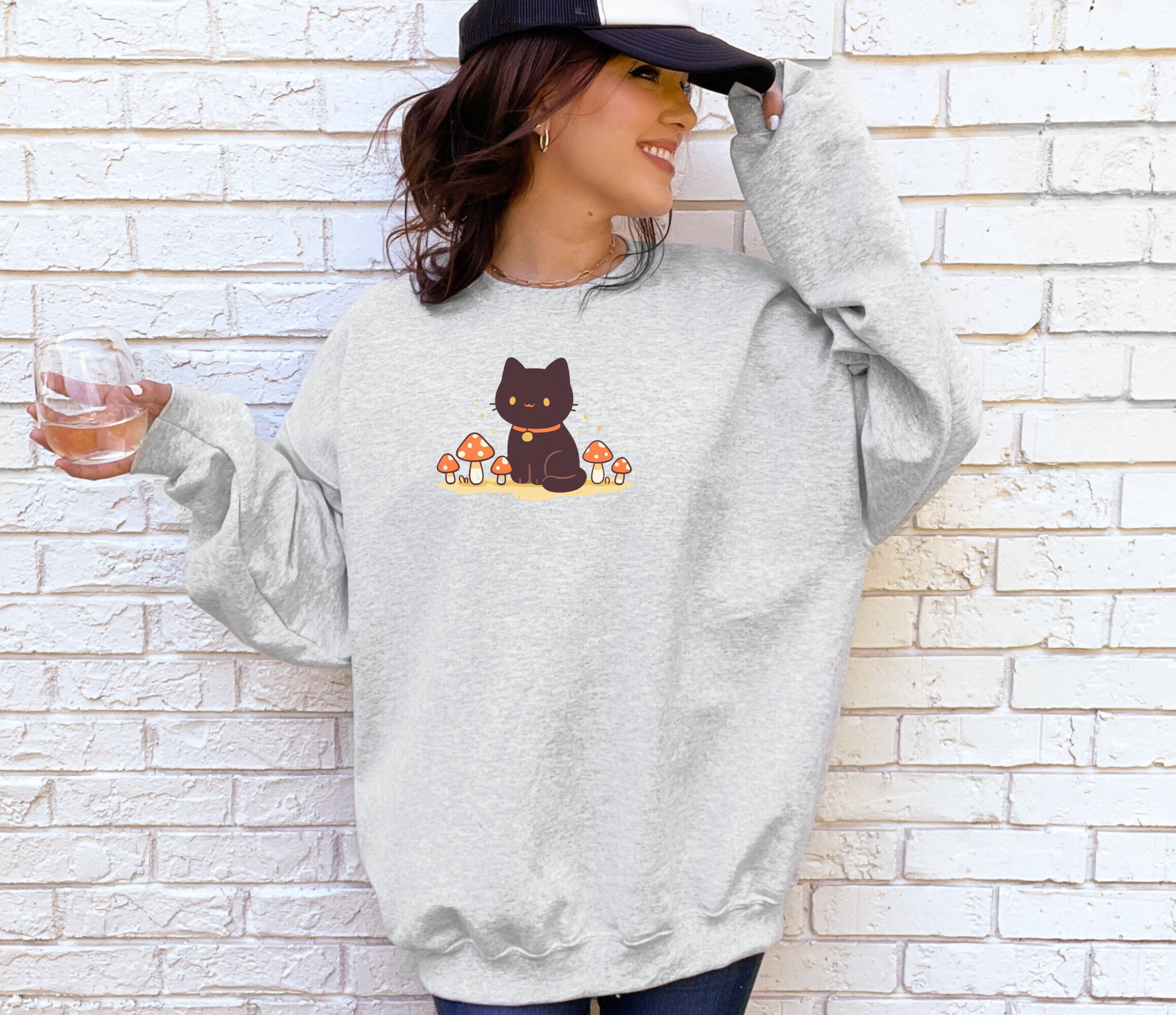 A cozy Comfort Colors sweatshirt featuring a cute black cat sitting among red mushrooms, perfect for cottagecore and witchy aesthetic lovers.