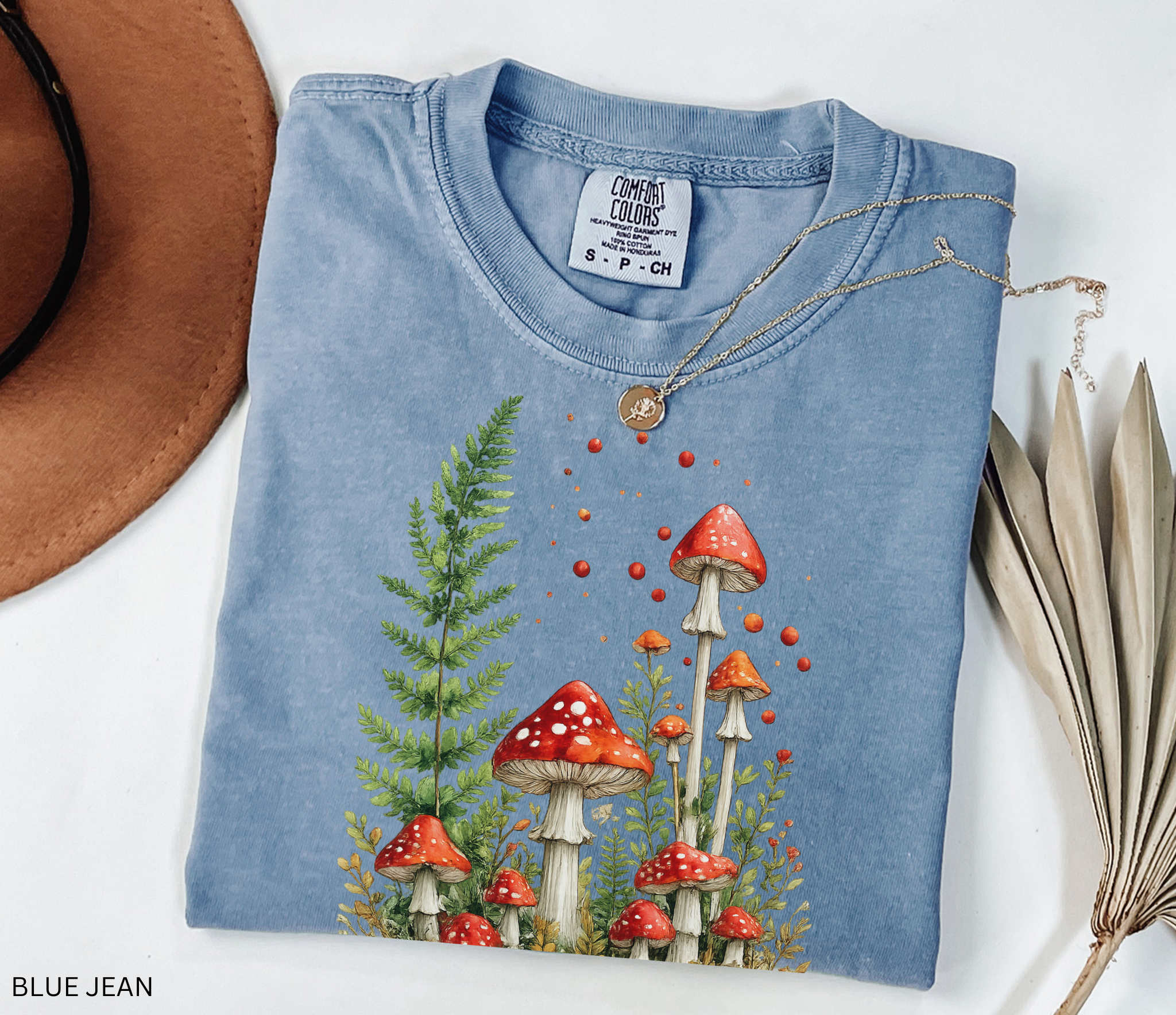Whimsical watercolor illustration of red fly agaric mushrooms surrounded by lush green ferns and woodland plants in a magical cottagecore fairy forest aesthetic.
