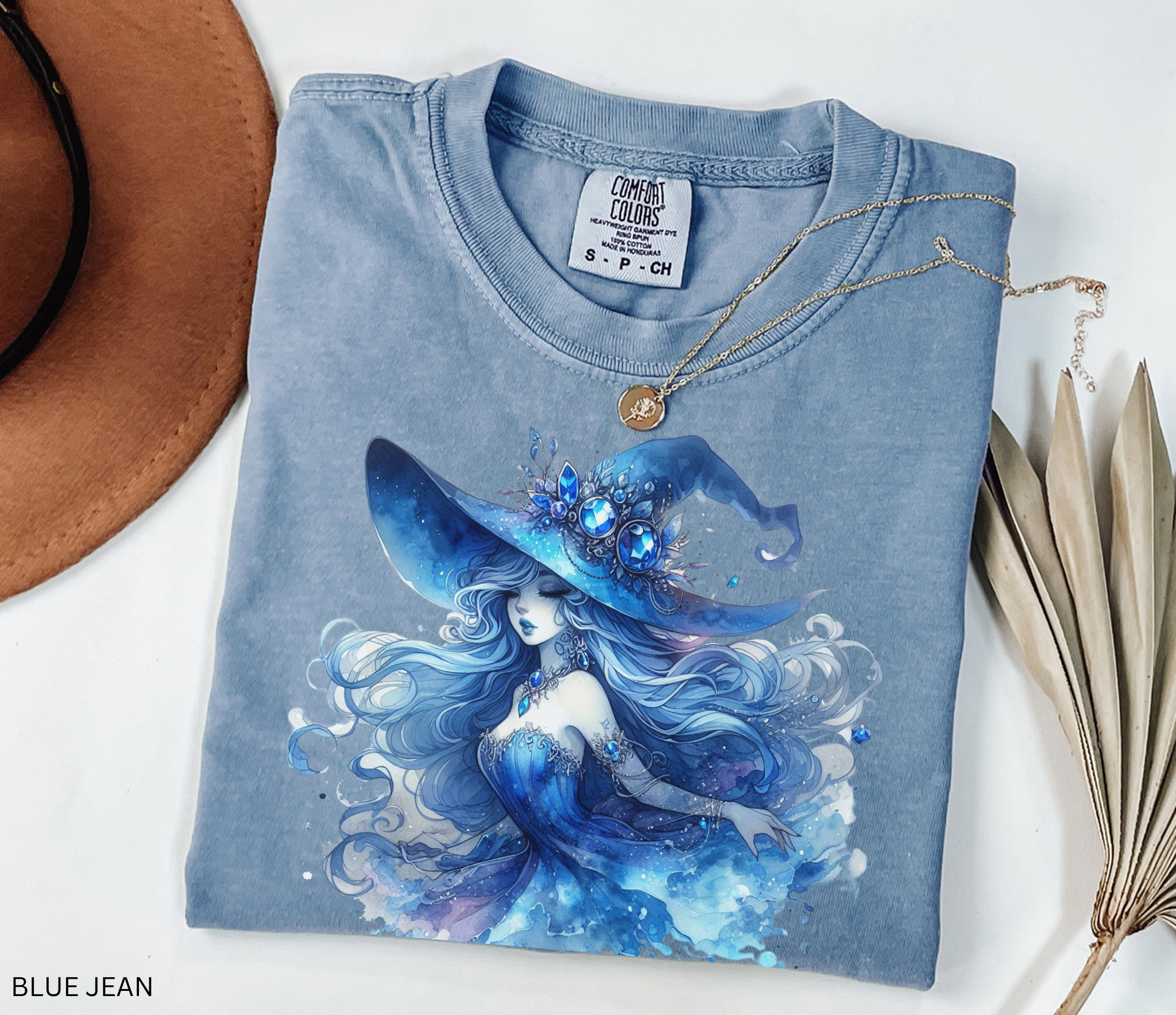 Watercolor fantasy illustration of a moonlit sapphire witch with flowing silver-blue hair, glowing gemstone jewelry, and a large enchanted blue hat surrounded by magical celestial details in a whimsical fairycore style.