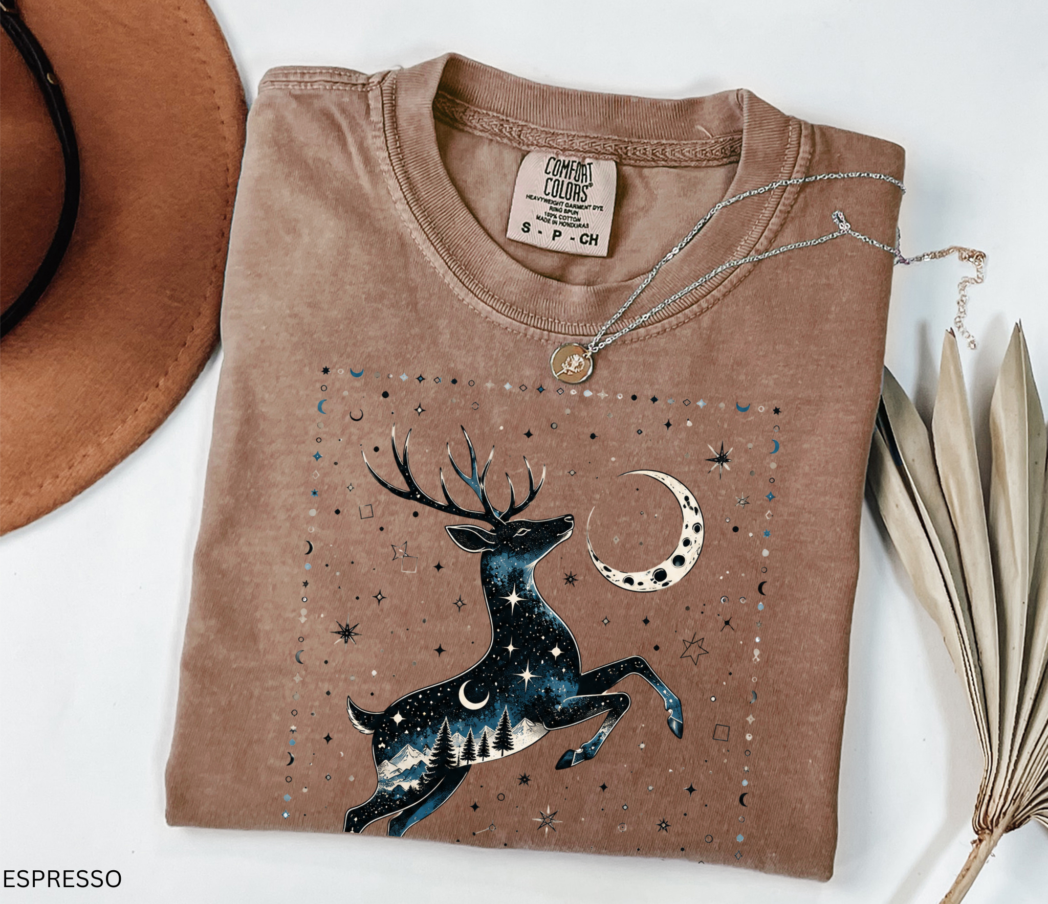 Celestial stag illustration filled with stars, moon phases, pine trees, and mountain scenery beneath a crescent moon in a mystical night-sky design.
