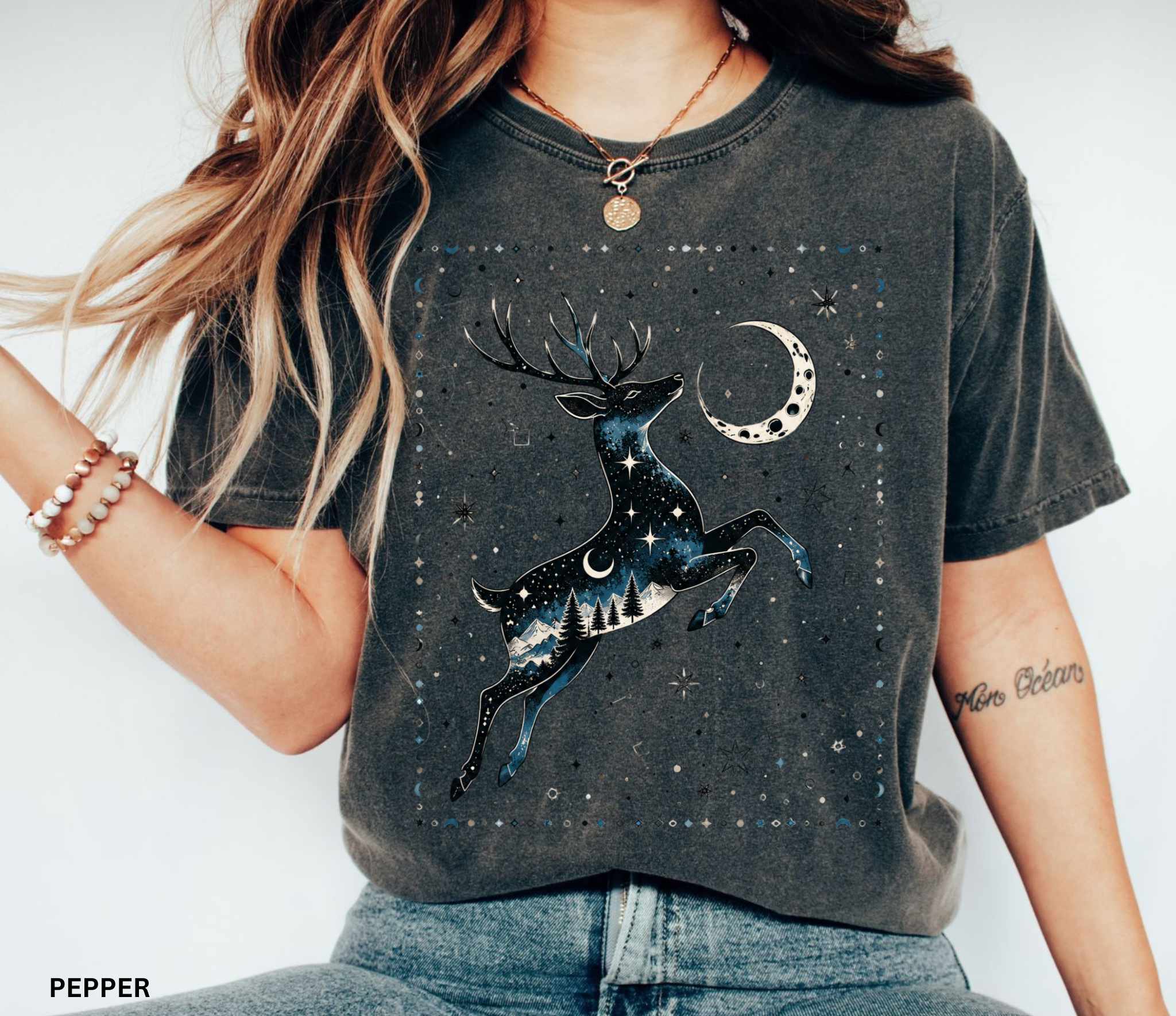 Celestial stag illustration filled with stars, moon phases, pine trees, and mountain scenery beneath a crescent moon in a mystical night-sky design.