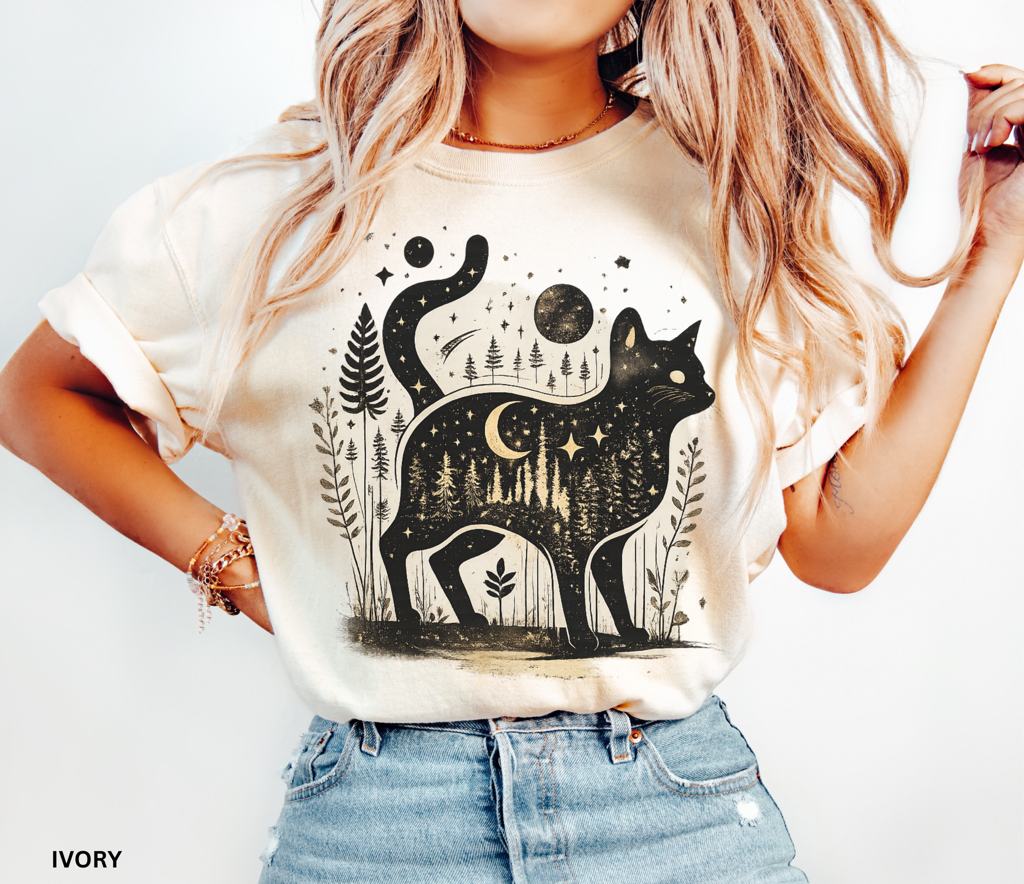 Comfort Colors cottagecore shirt featuring a magical black cat silhouette filled with a moonlit forest scene, stars, crescent moon, and woodland details. Available in orchid, blue jean, espresso, and ivory colors.