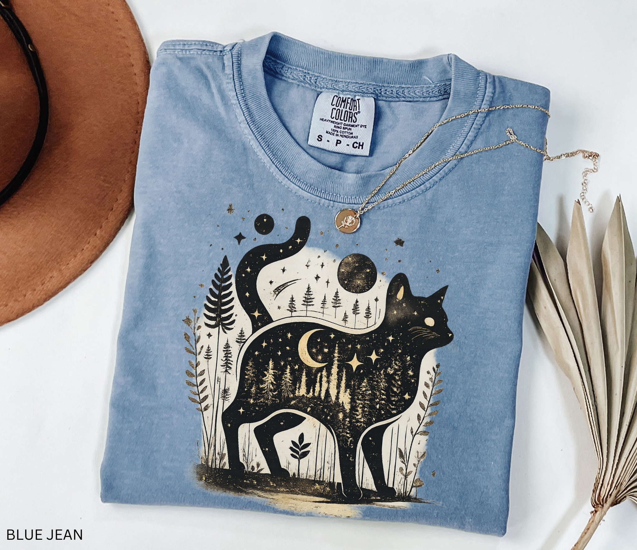 Comfort Colors cottagecore shirt featuring a magical black cat silhouette filled with a moonlit forest scene, stars, crescent moon, and woodland details. Available in orchid, blue jean, espresso, and ivory colors.