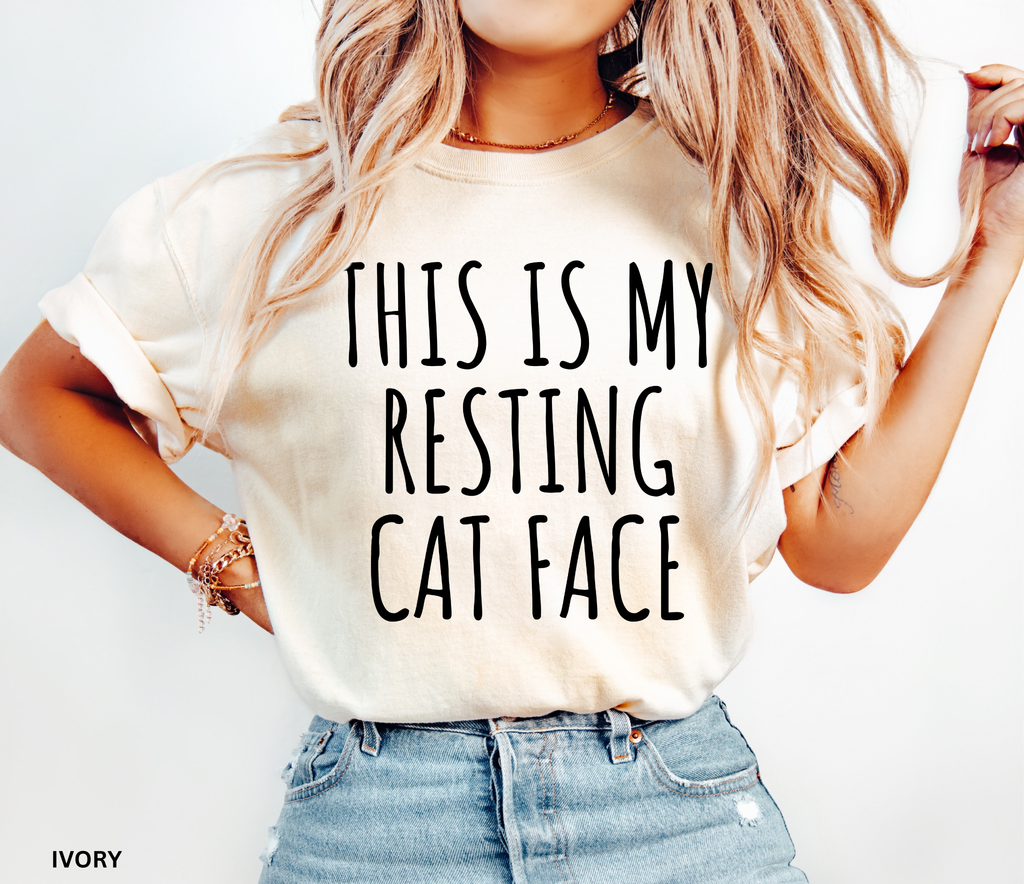 Person wearing a white t-shirt with 'THIS IS MY RESTING CAT FACE' text, standing against a plain background.