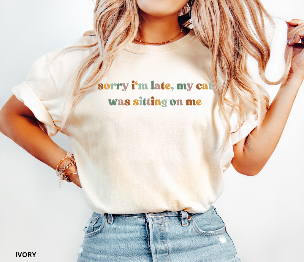 Funny cat lover graphic t-shirt featuring the colorful quote "Sorry I'm Late, My Cat Was Sitting on Me." A humorous gift for cat moms, cat dads, and pet owners.