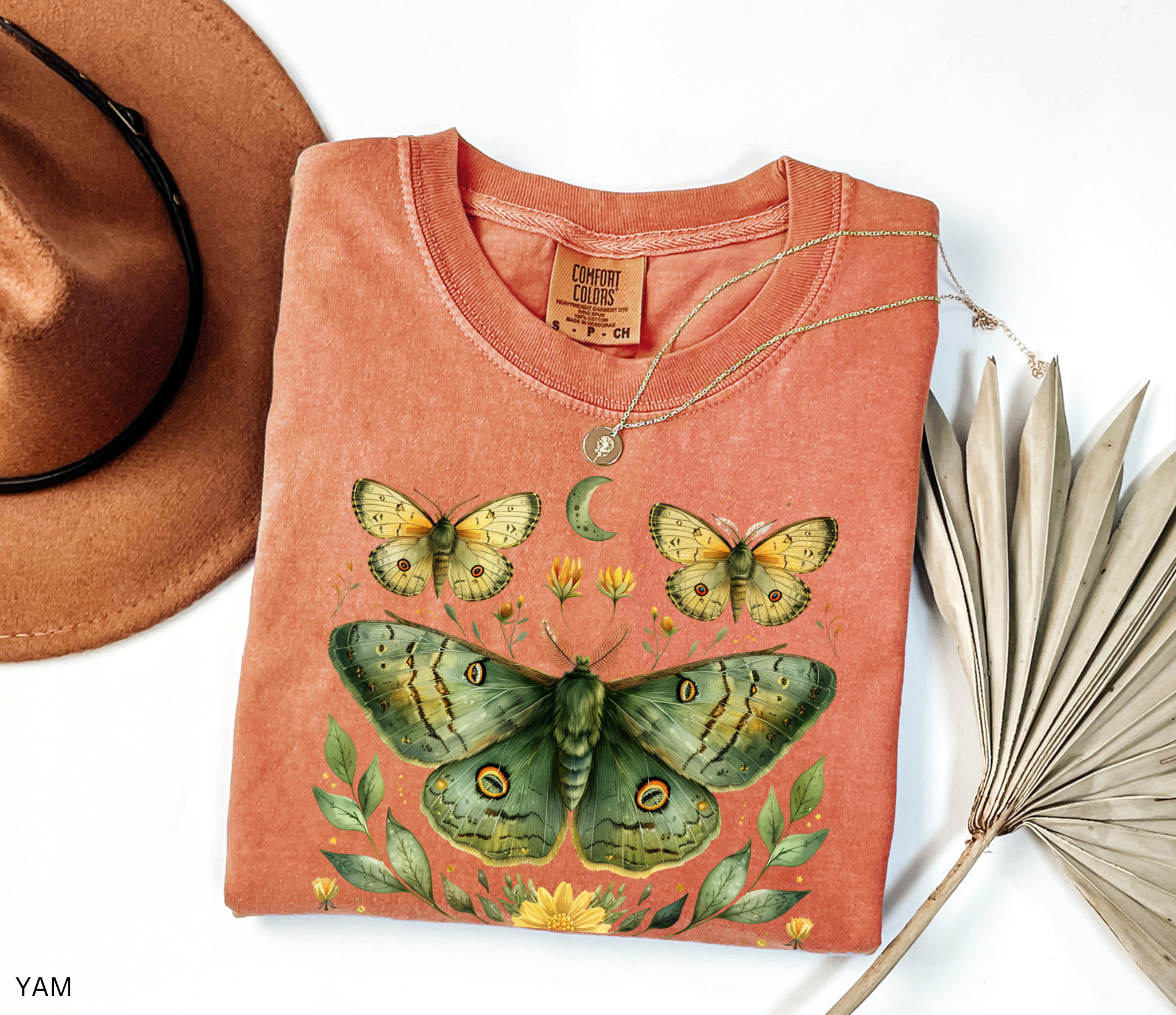 Comfort Colors graphic t-shirt featuring a detailed green luna moth surrounded by wildflowers, leaves, smaller moths, and a crescent moon in a vintage botanical cottagecore illustration