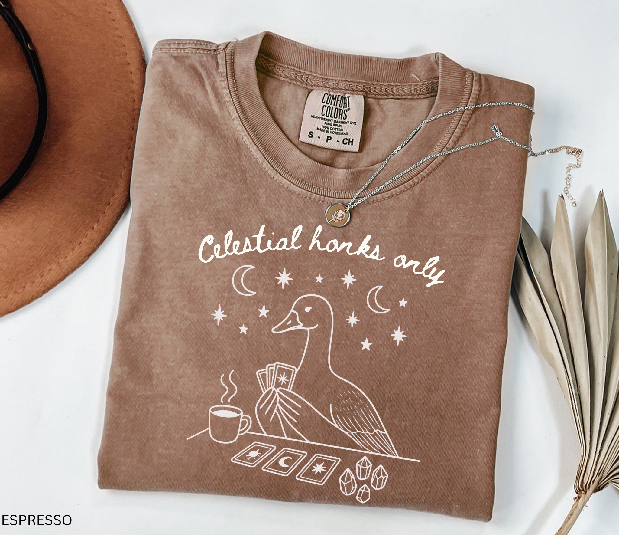 Funny witchy goose graphic featuring a celestial goose holding tarot cards beside a steaming cup of tea, surrounded by stars, crescent moons, and crystals. The design includes the phrase "Celestial Honks Only," making it a whimsical cottagecore and tarot-inspired shirt for goose lovers, tea drinkers, and mystical souls.