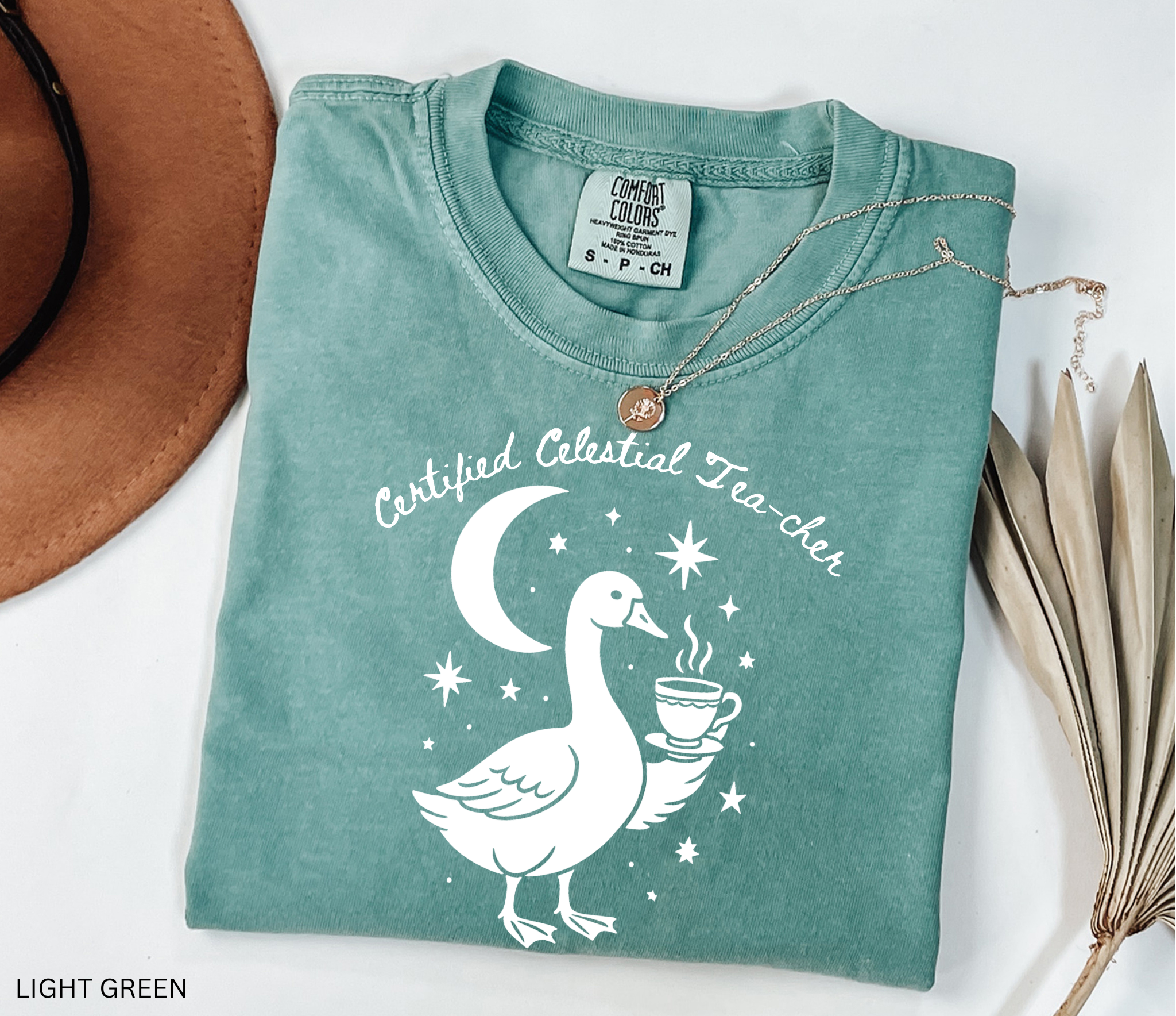 Certified Celestial Tea-cher Comfort Colors t-shirt featuring a whimsical goose holding a steaming teacup beneath a crescent moon and stars, perfect for witchy teachers, tea lovers, and cottagecore fashion.