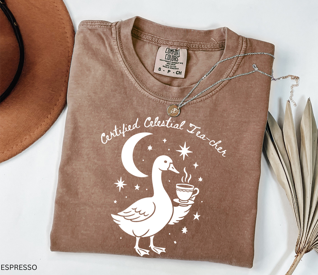 Certified Celestial Tea-cher Comfort Colors t-shirt featuring a whimsical goose holding a steaming teacup beneath a crescent moon and stars, perfect for witchy teachers, tea lovers, and cottagecore fashion.