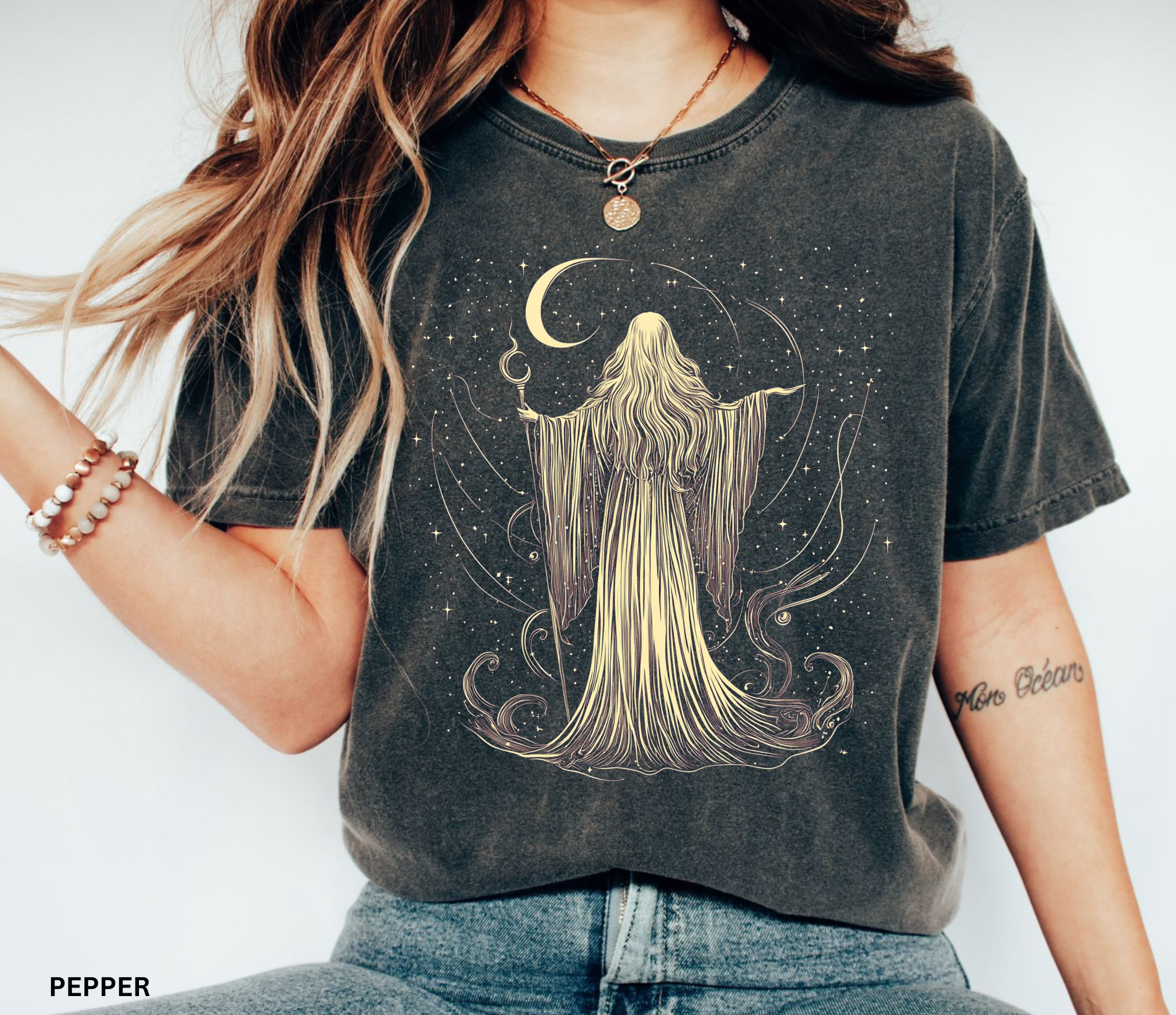Vintage Comfort Colors t-shirt featuring an elegant moon priestess standing beneath a crescent moon surrounded by stars and flowing celestial magic. Available in Blue Jean, Espresso, Pepper, and Black.