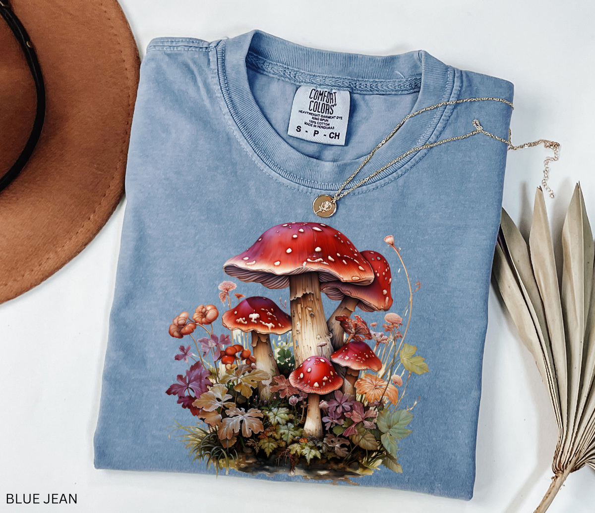 Red mushroom graphic t-shirt featuring a detailed cluster of woodland toadstools surrounded by autumn foliage and botanical details.