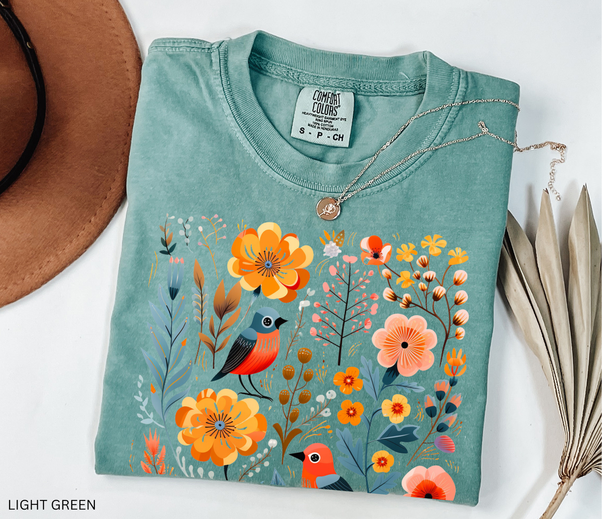 A whimsical Nordic folk-art fox Comfort Colors shirt featuring floral and botanical details in warm orange and muted blue tones.