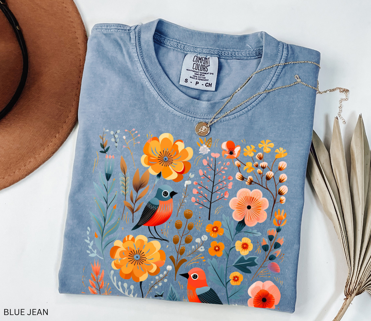 A whimsical Nordic folk-art fox Comfort Colors shirt featuring floral and botanical details in warm orange and muted blue tones.