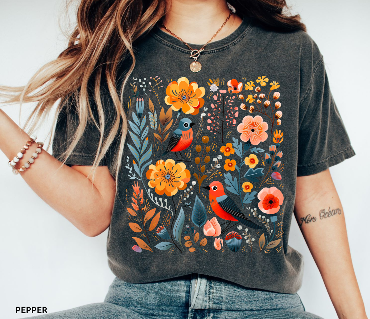 A whimsical Nordic folk-art fox Comfort Colors shirt featuring floral and botanical details in warm orange and muted blue tones.